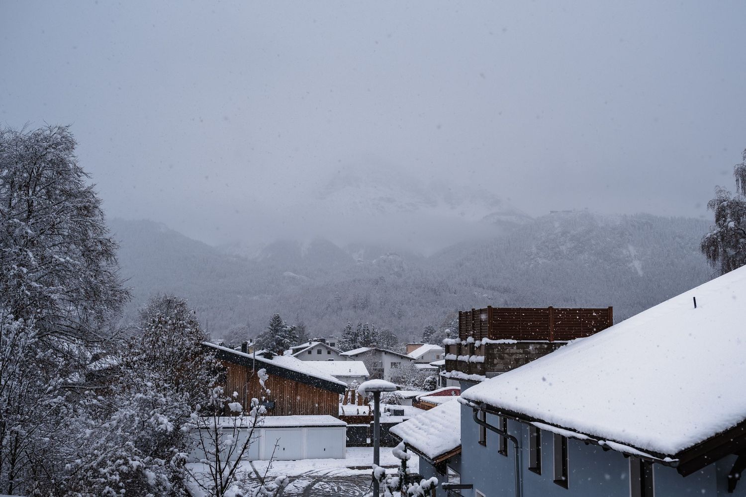 Snow covered mountain village with traditional wooden houses nestled in a scenic winter landscape.