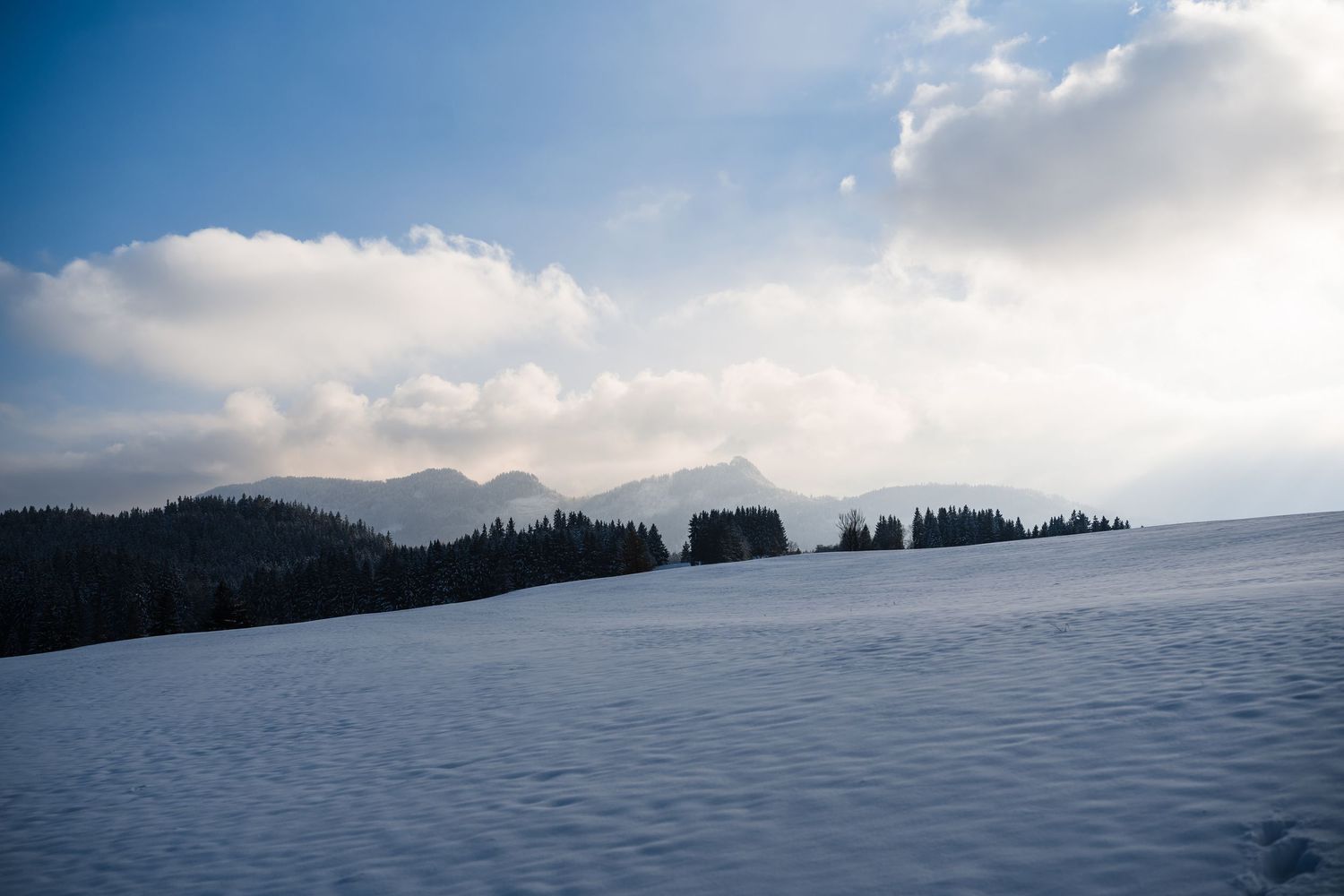 Scenic mountain landscape panorama with snow-covered peaks and dramatic cloudy sky during winter season.