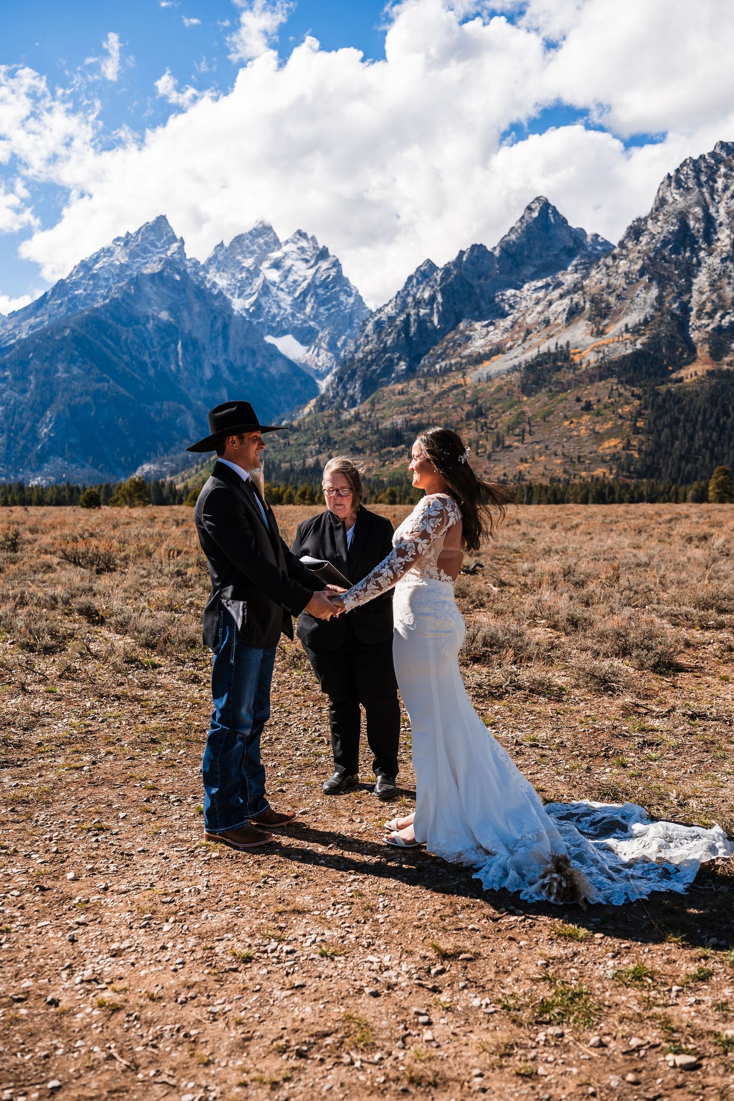 A wedding ceremony unfolds against the dramatic backdrop of snow-capped mountains in Grand Teton National Park.