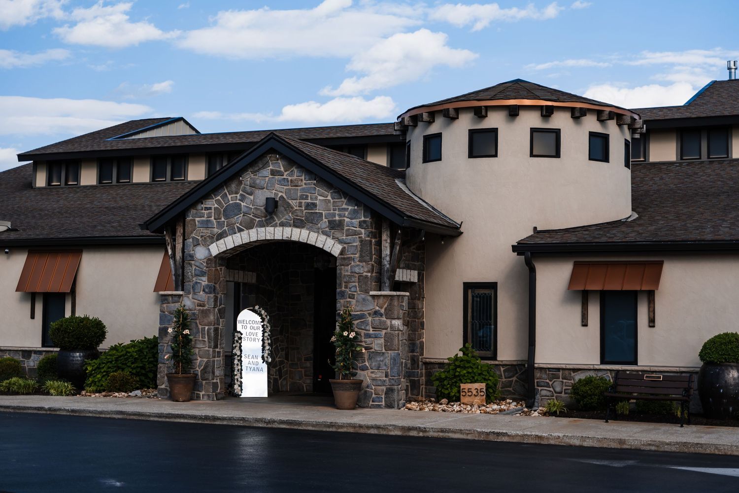Elegant wedding venue exterior featuring stone archway, stucco walls, and circular tower architecture.