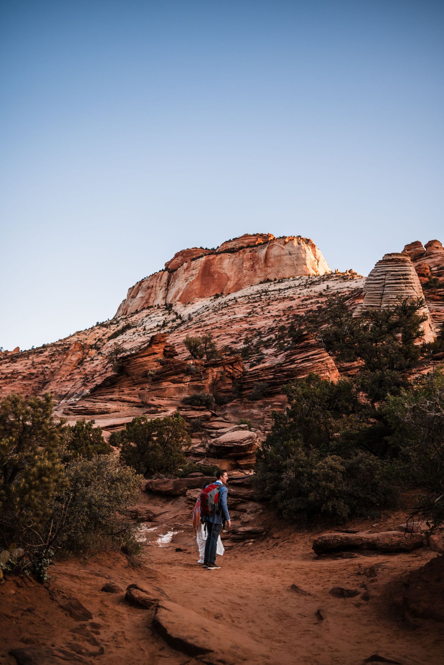 Couple hiking red rock trail at Zion National Park during golden hour before their elopement.