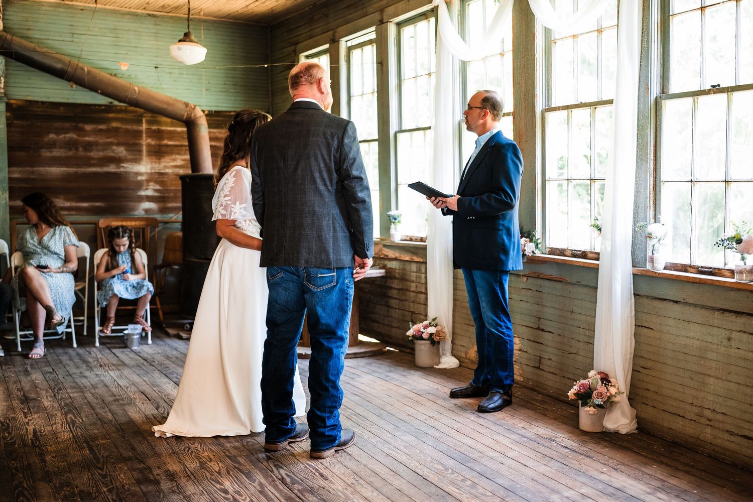 Wedding couple photographed in a rustic wooden venue with large windows and natural light.