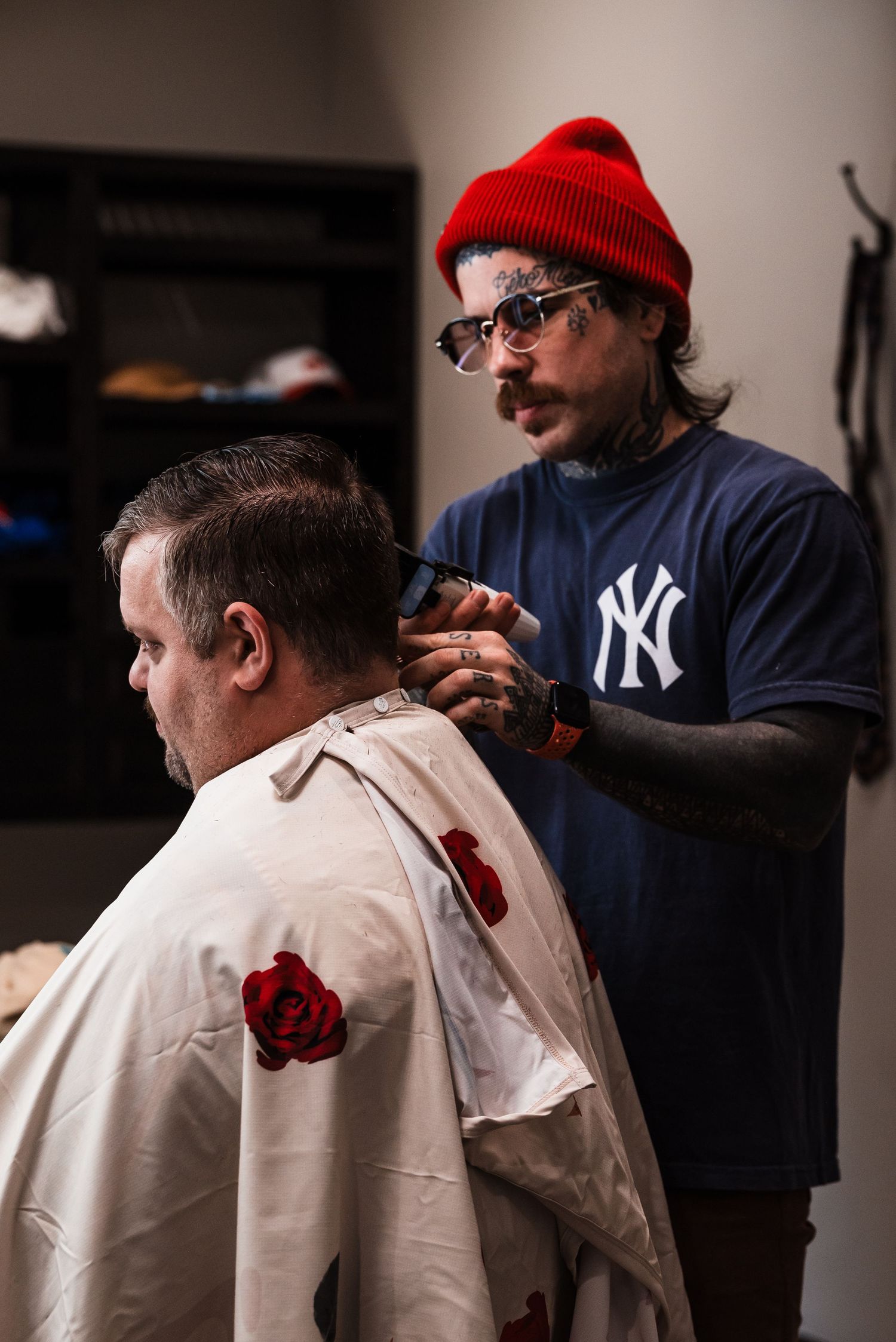 Person in white getting dressed with help while someone in a Yankees shirt and red beanie assists.