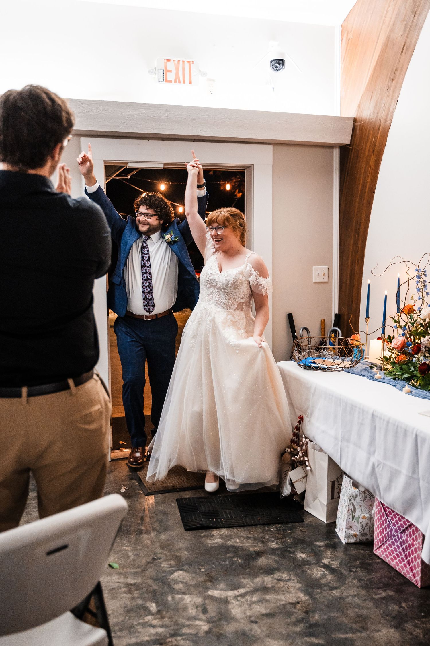 Newlyweds make grand entrance at reception with raised arms in celebration.