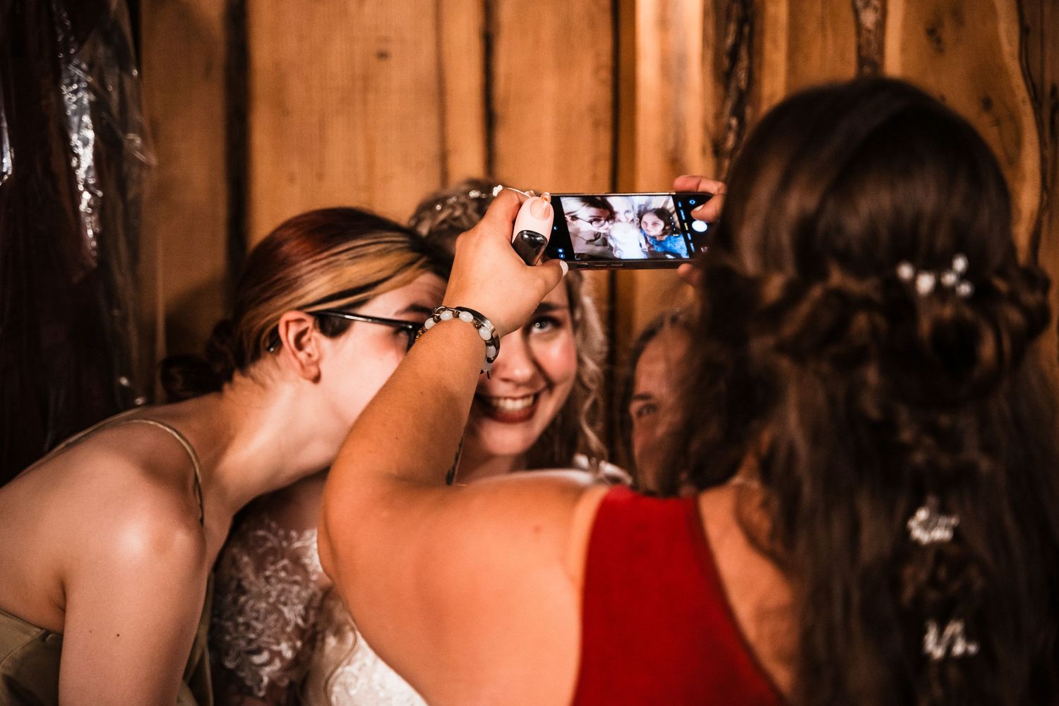 Guests capture candid moments on phones at an indoor wedding reception.