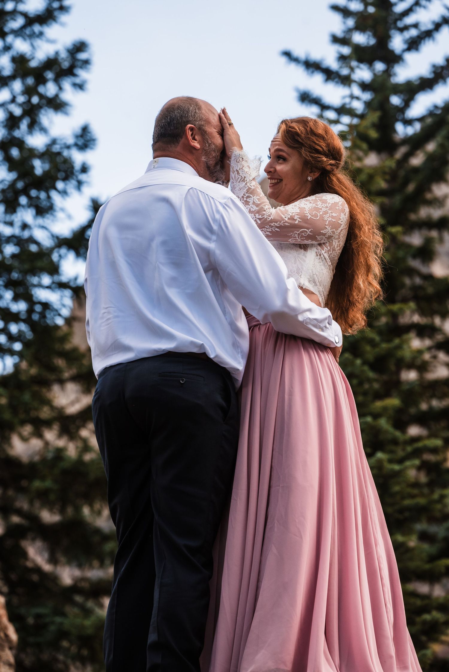 An intimate moment shared between a couple against a backdrop of mountain scenery.