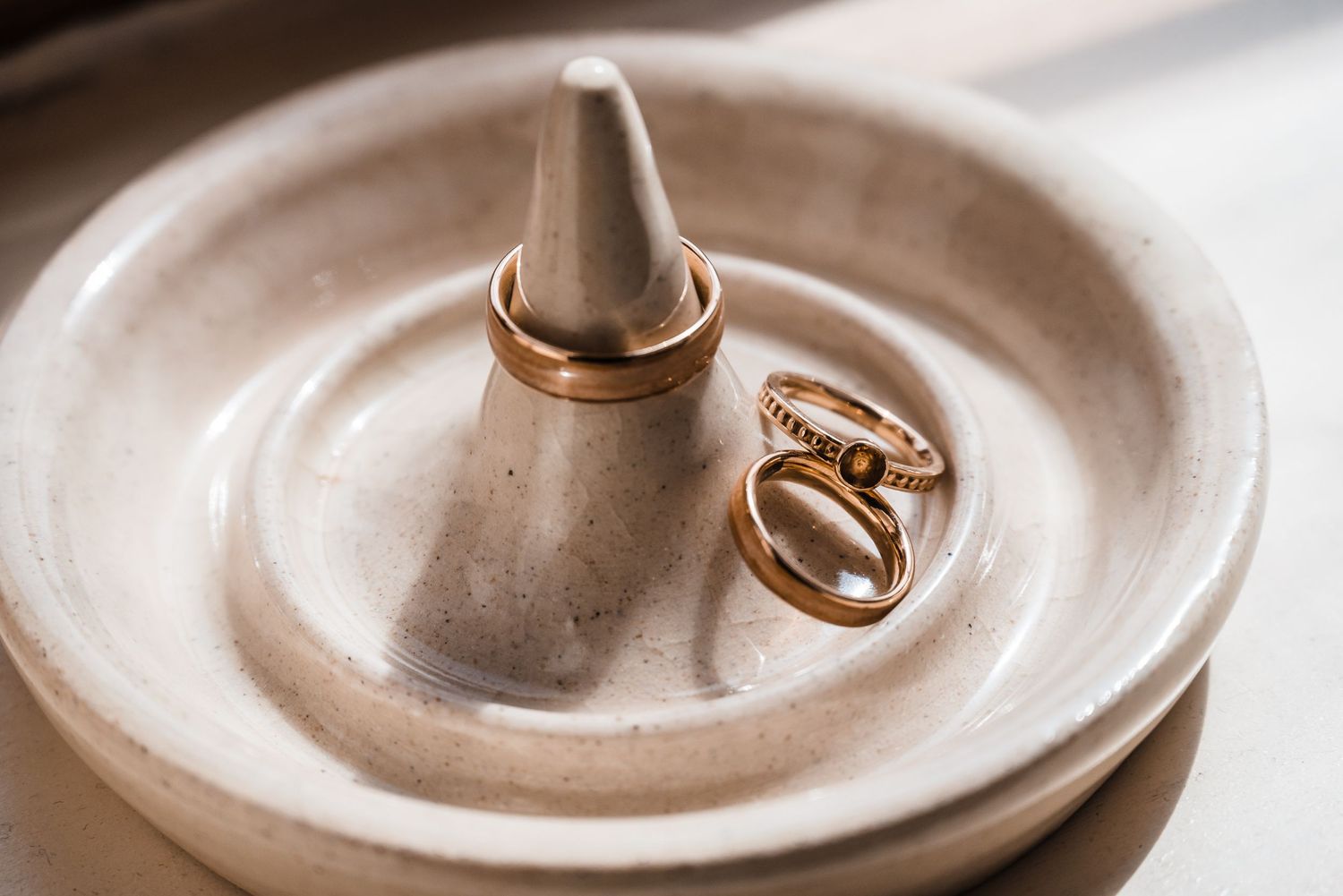 Wedding rings displayed on a white ceramic ring holder.