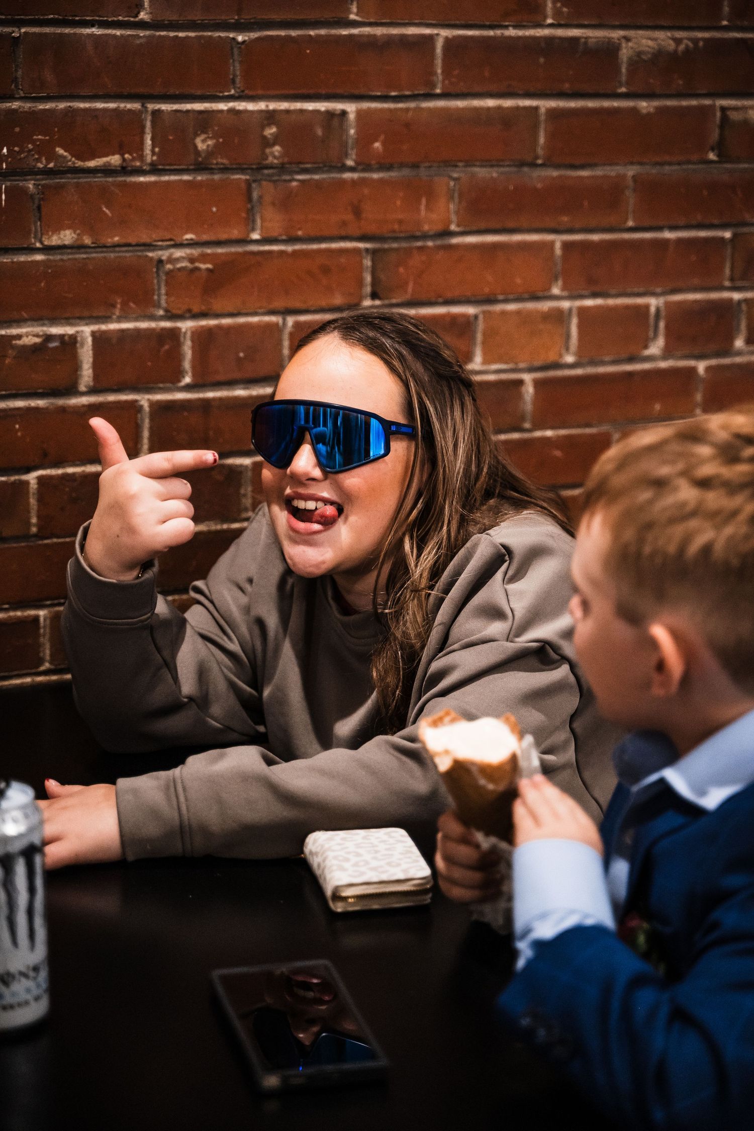 People enjoying ice cream treats at table against brick wall background.