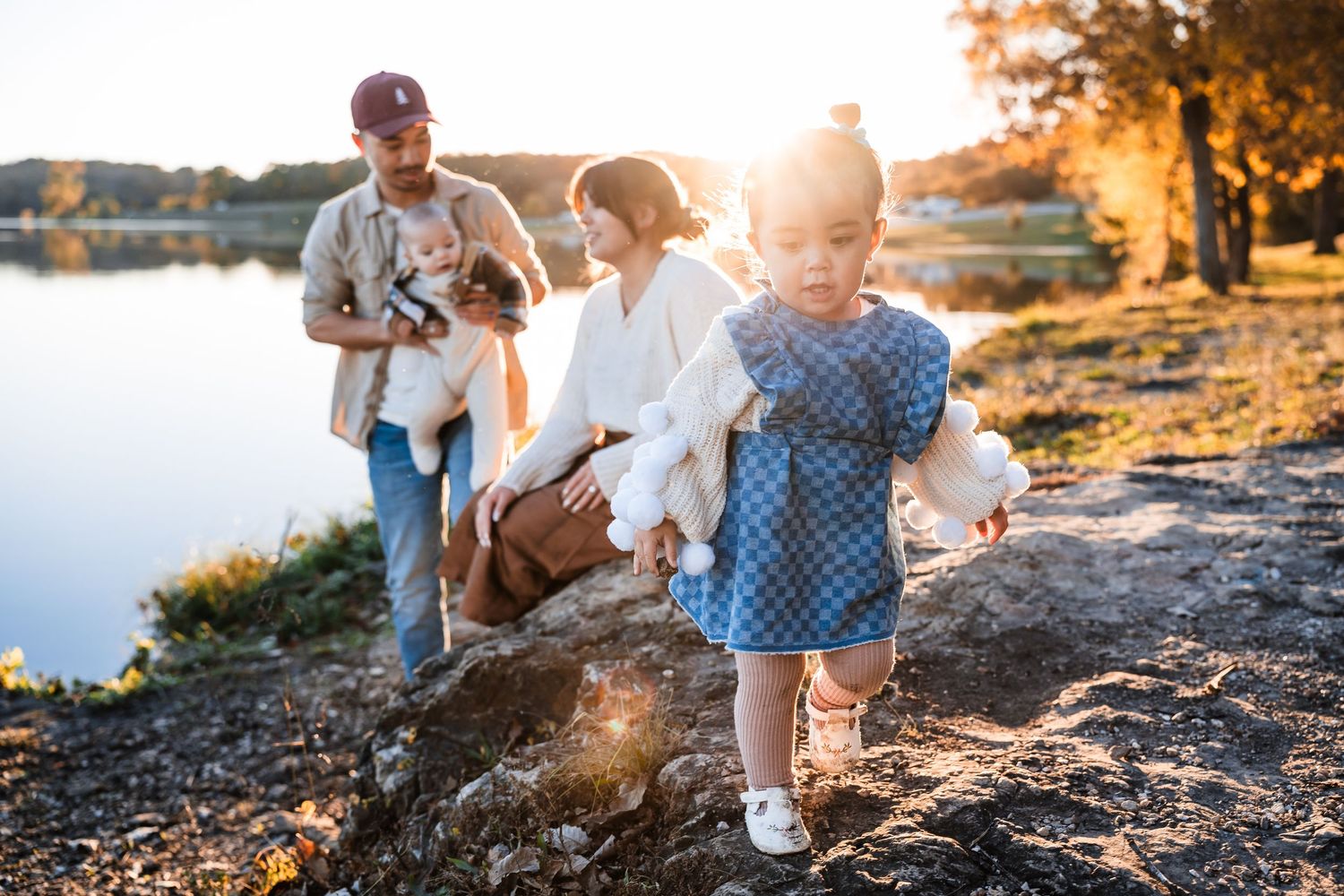 People enjoying a warm sunset on rocky terrain near a lake.
