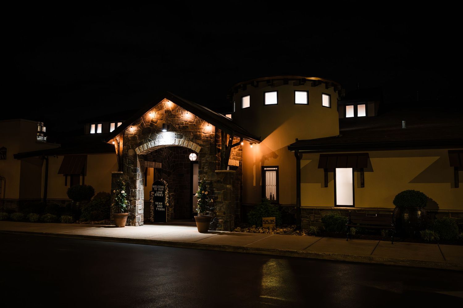 Warmly lit venue entrance illuminated at night with golden lights and architectural details.