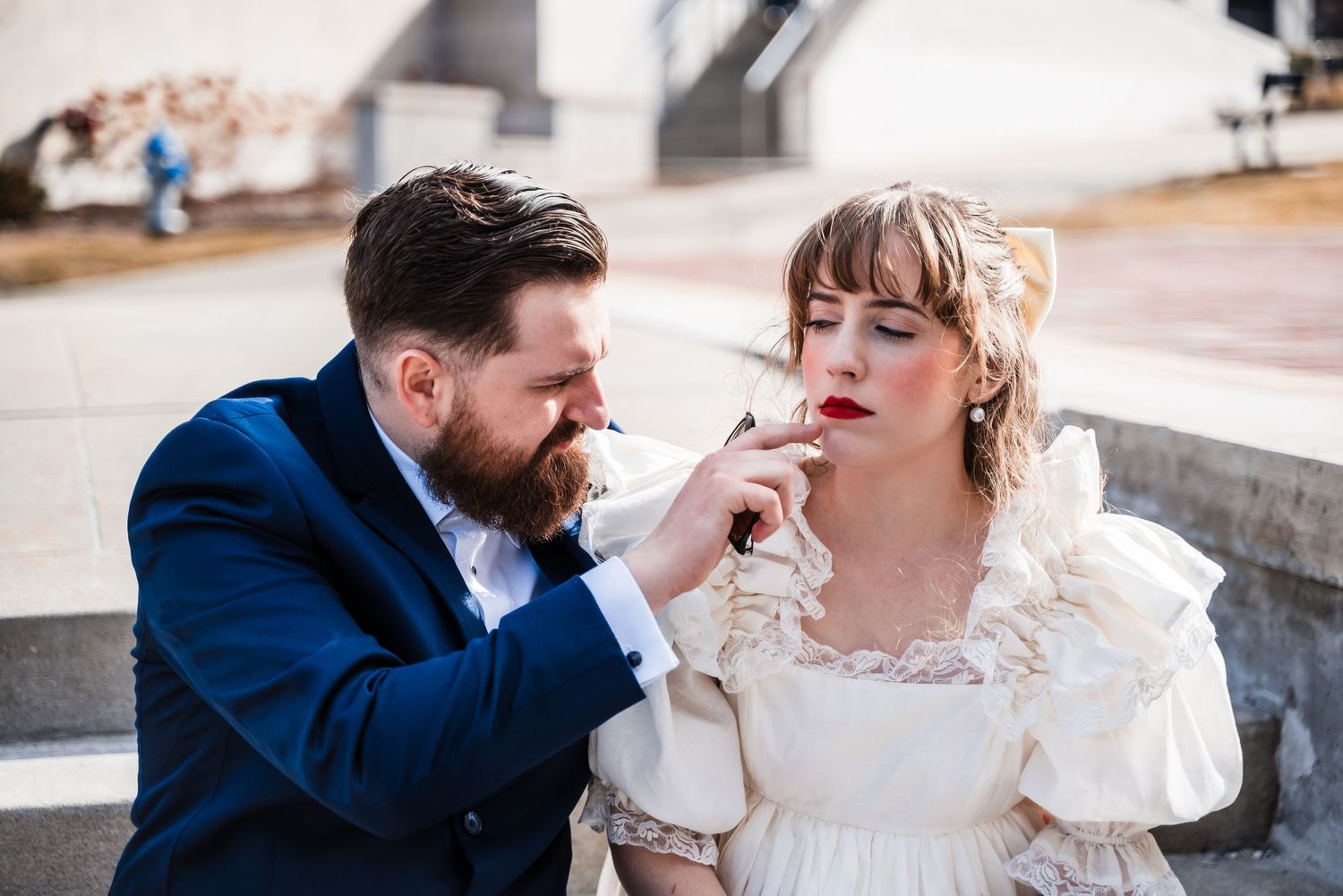 A tender moment between a couple in formal wear sitting on concrete steps.
