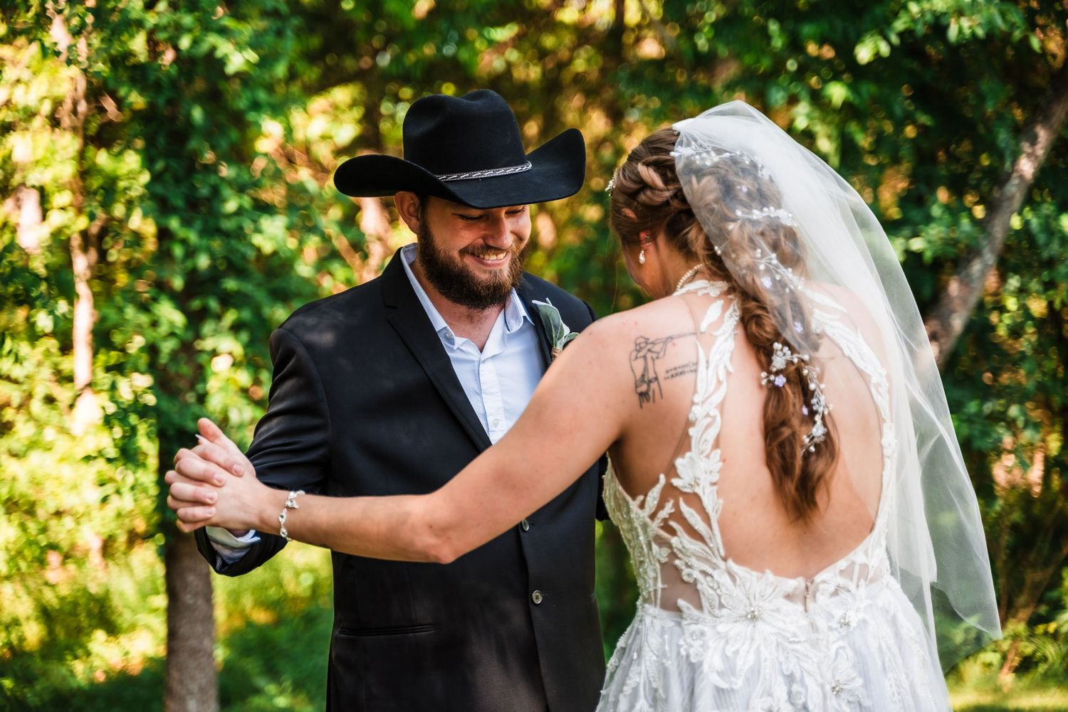 Newlywed couple shares a romantic first dance outdoors with sunlit greenery in the background.