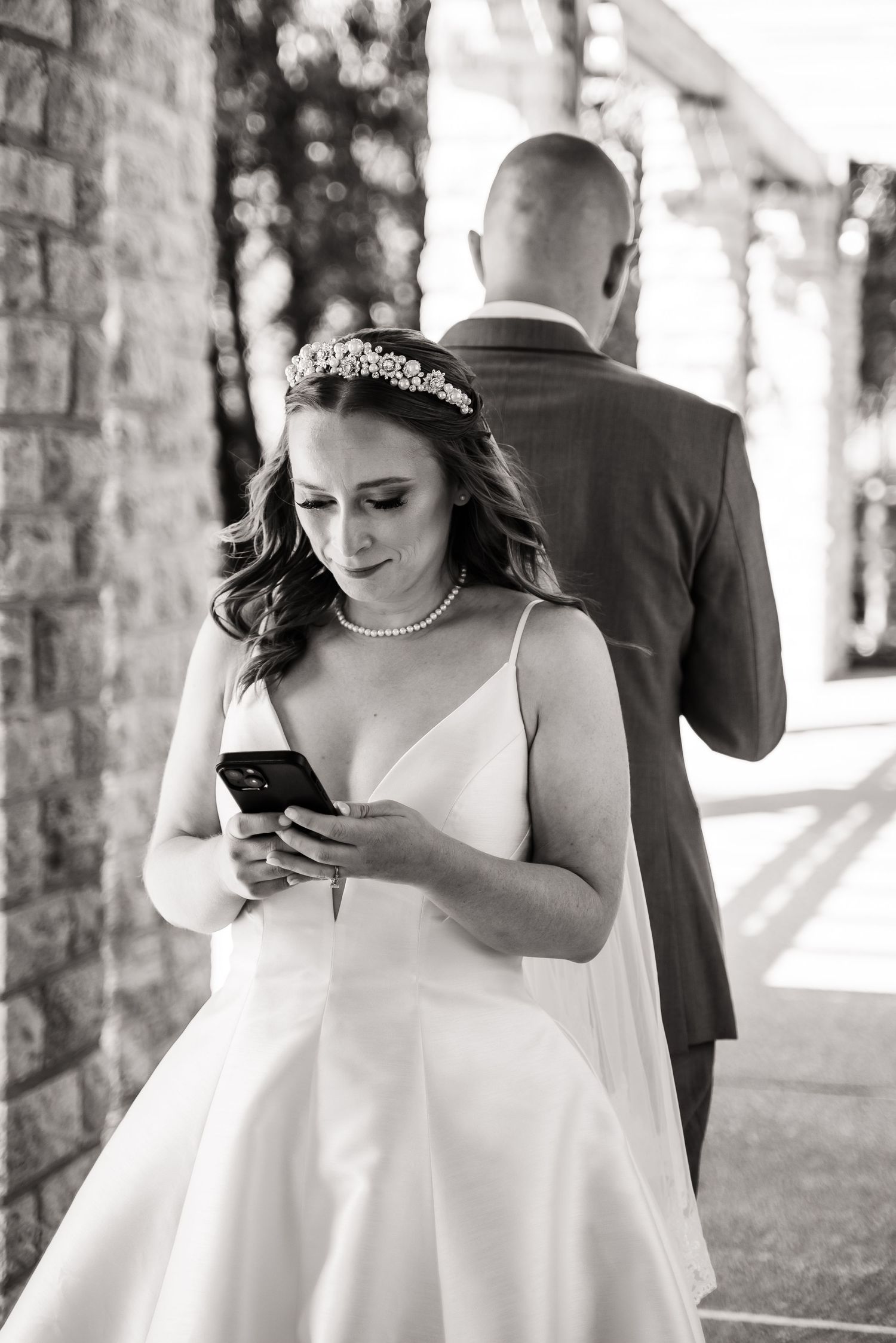 Wedding scene showing a phone moment during the celebration against a stone wall backdrop.