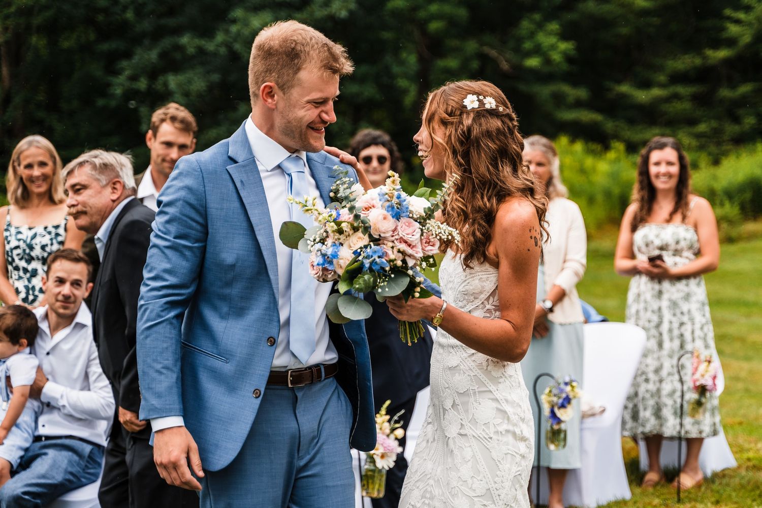 Wedding guests look on as newlyweds share their first moments together at an outdoor garden ceremony.