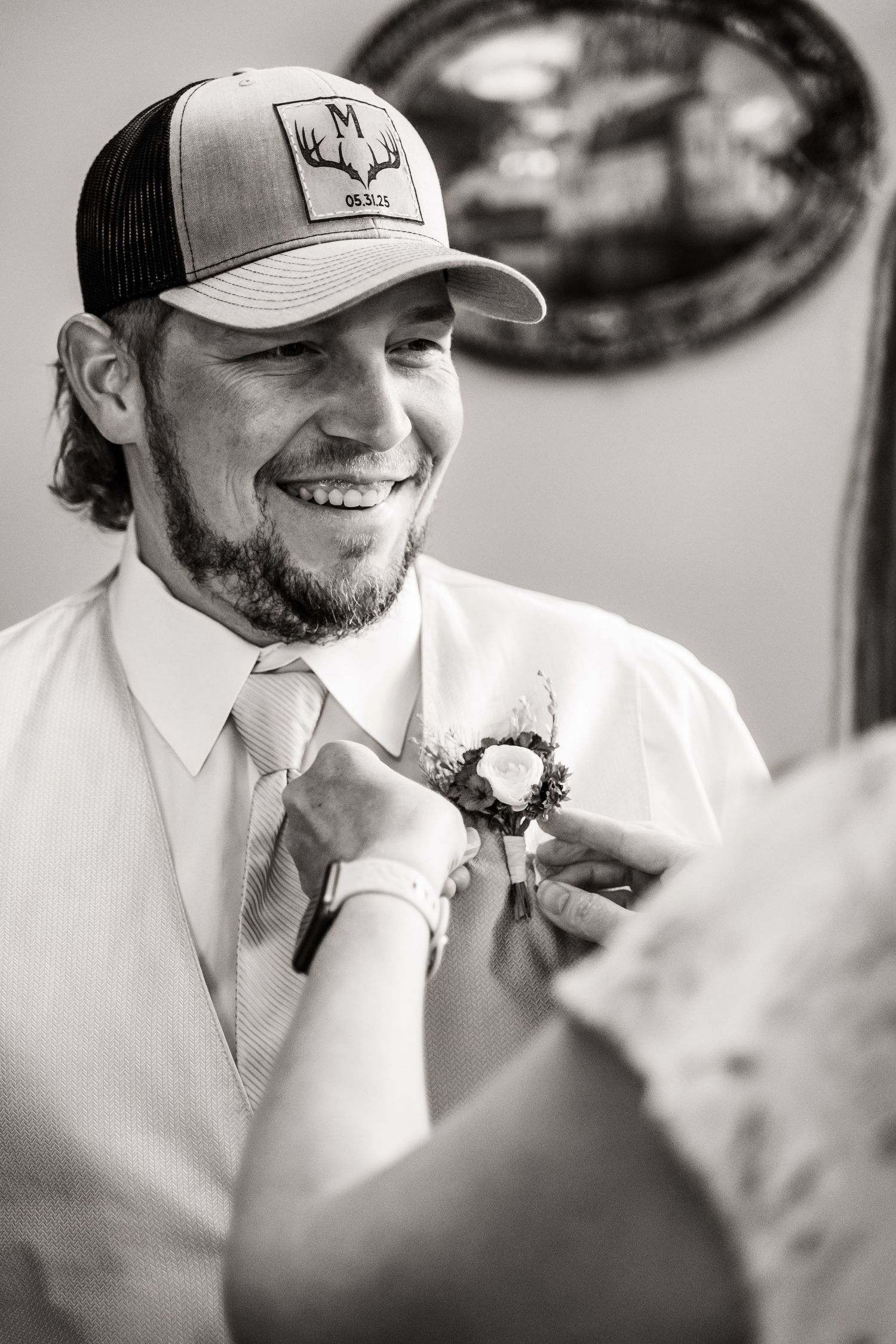 A boutonniere being pinned onto formal attire during wedding preparations.