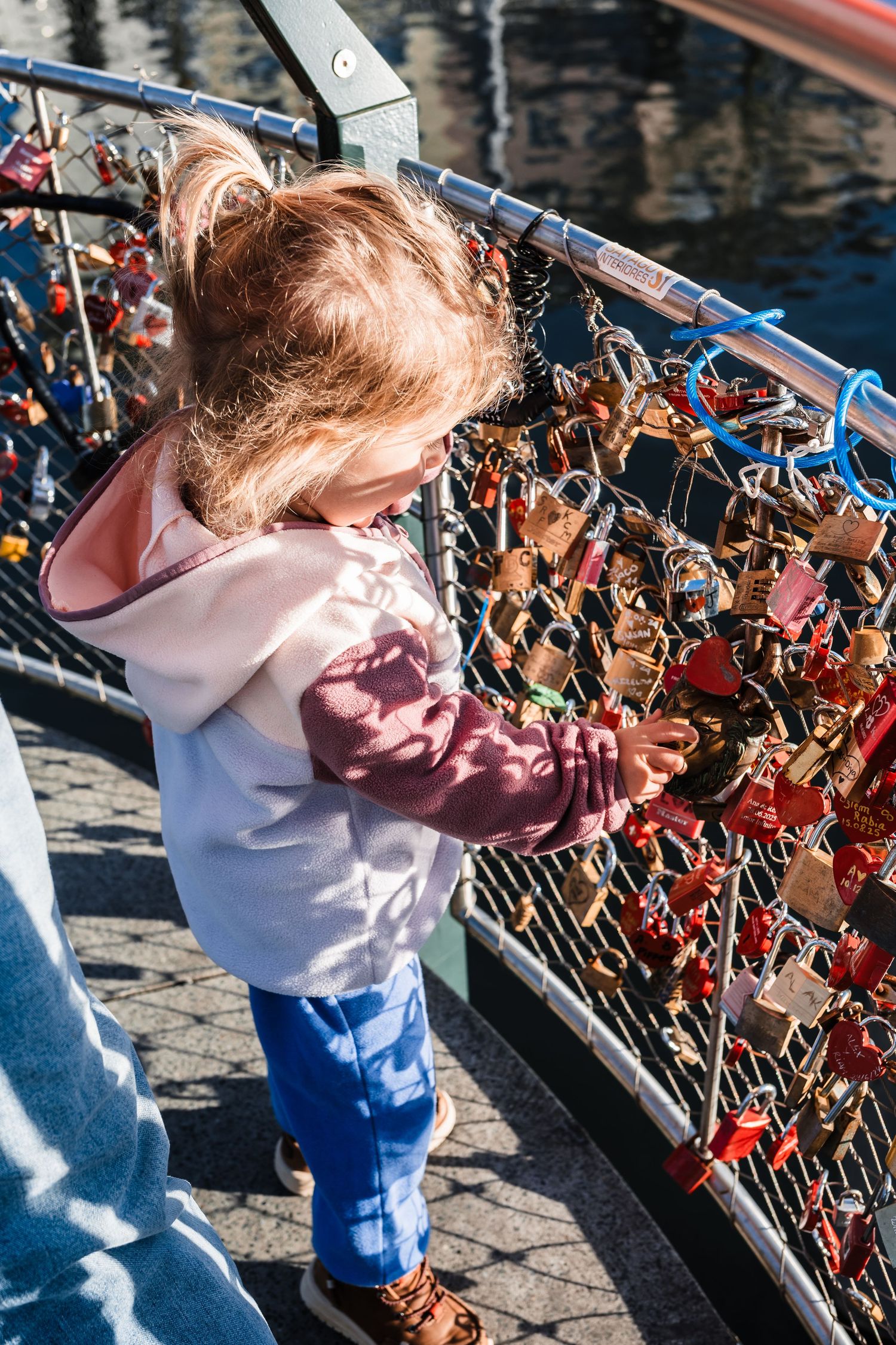 Close-up view of love locks attached to a bridge railing with blurred water in the background.