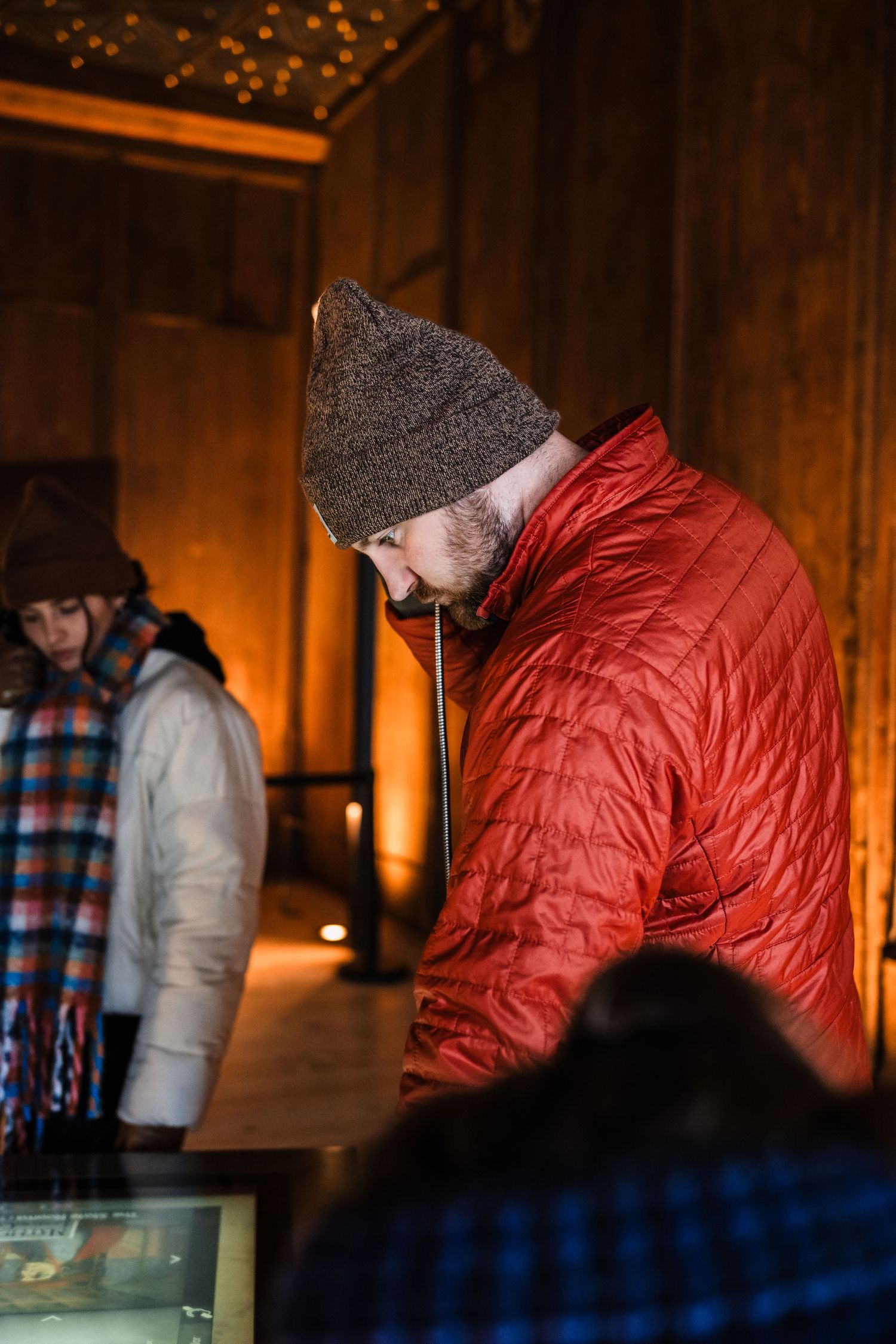 People in winter coats viewing exhibits in a warmly lit museum space.