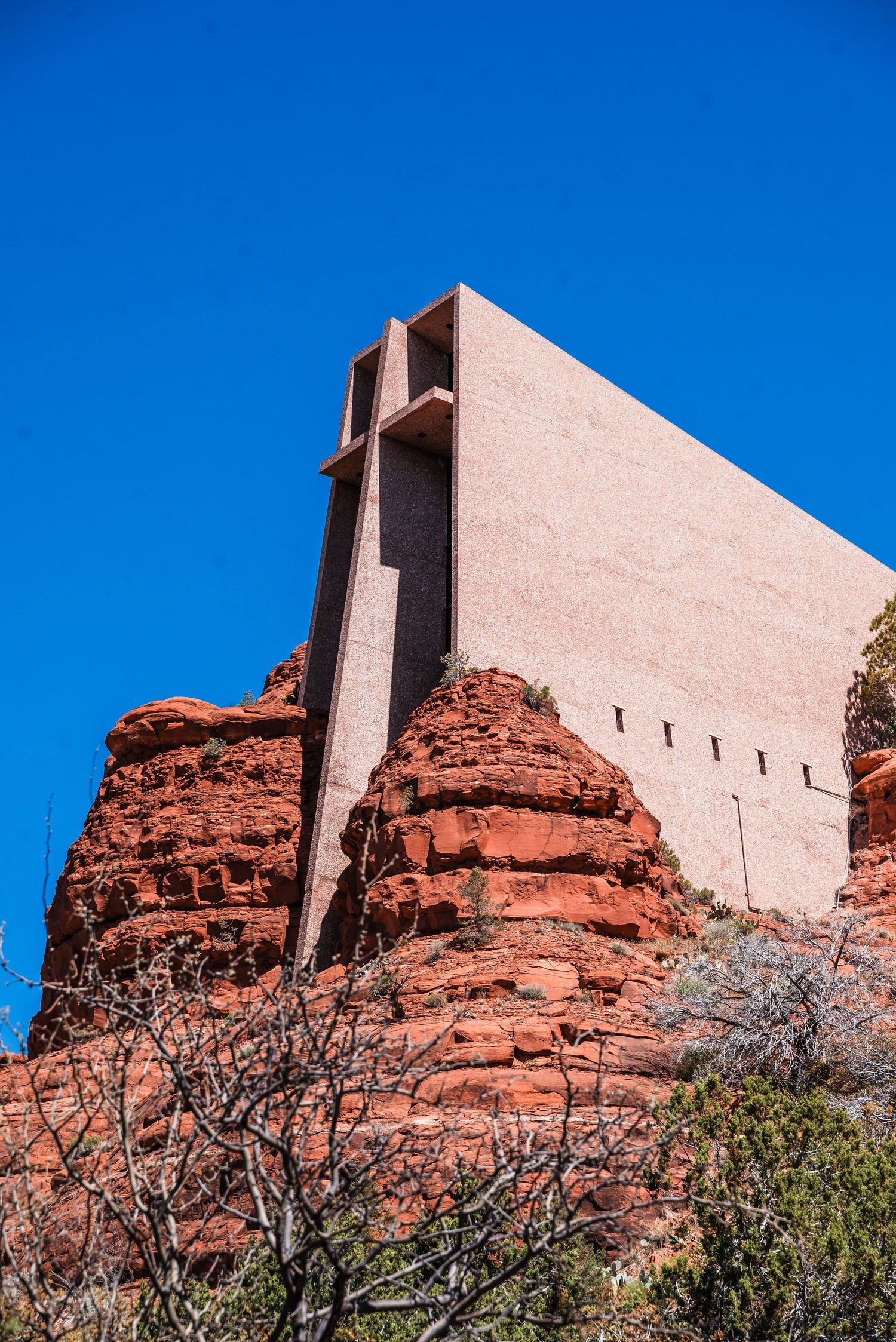 Chapel of the Holy Cross rises dramatically against red rock formations and blue sky in Sedona, Arizona.
