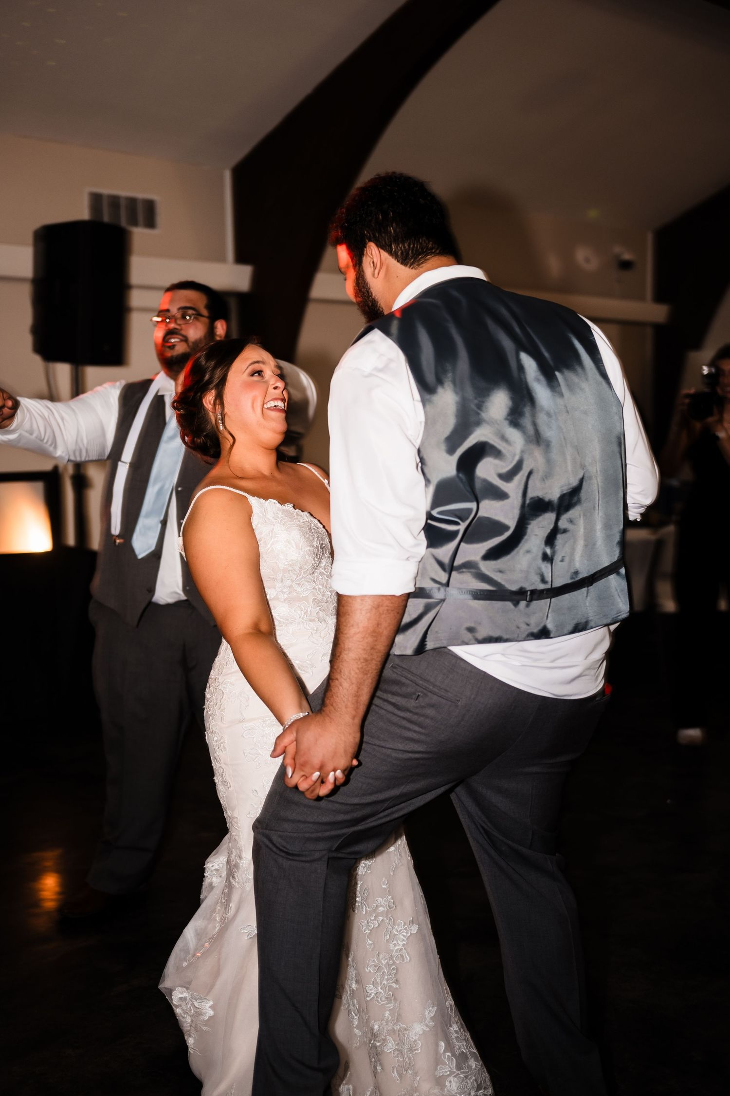 Wedding guests and couple dancing energetically during a joyful reception celebration.