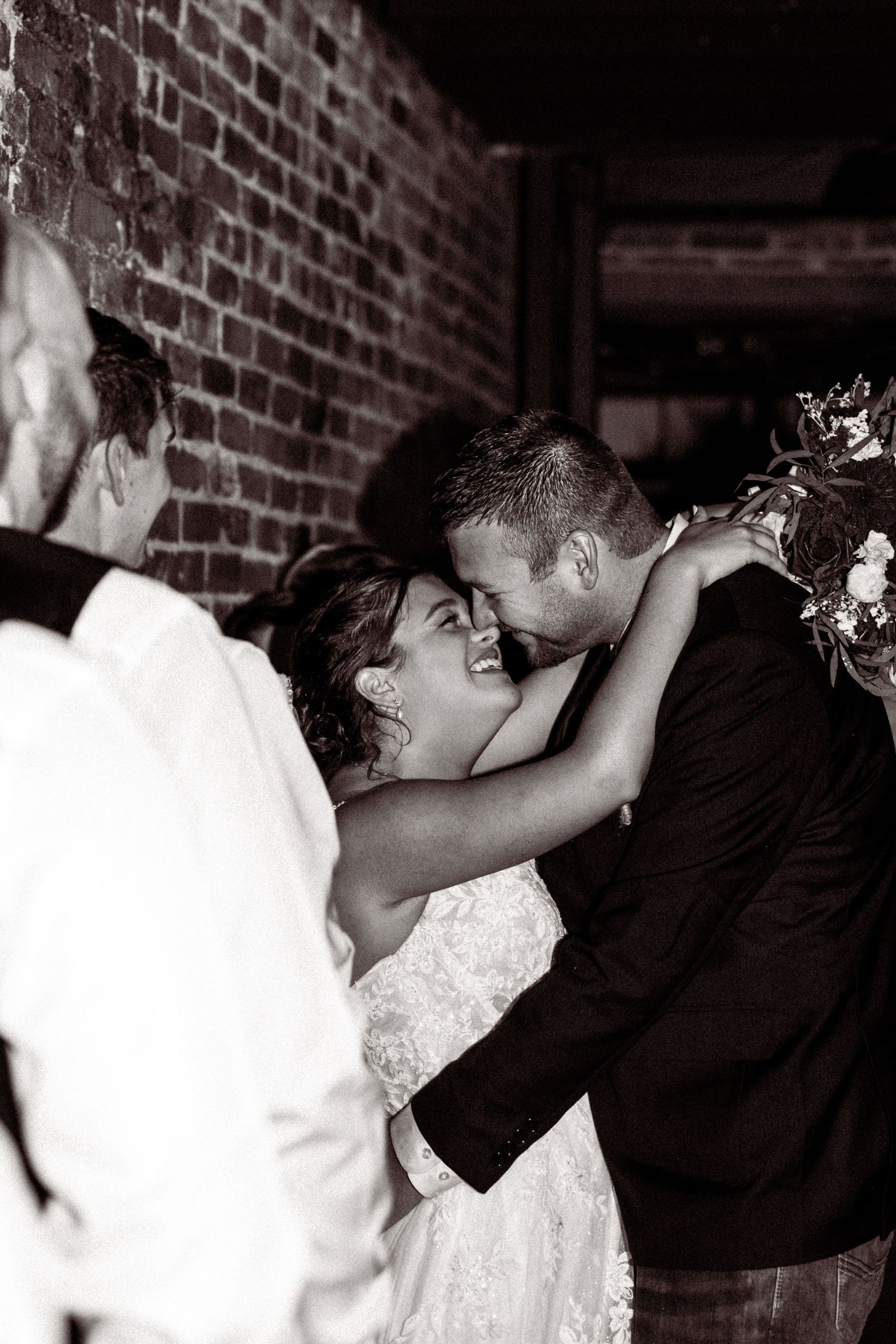 Black and white sequence of romantic wedding couple moments against brick wall.