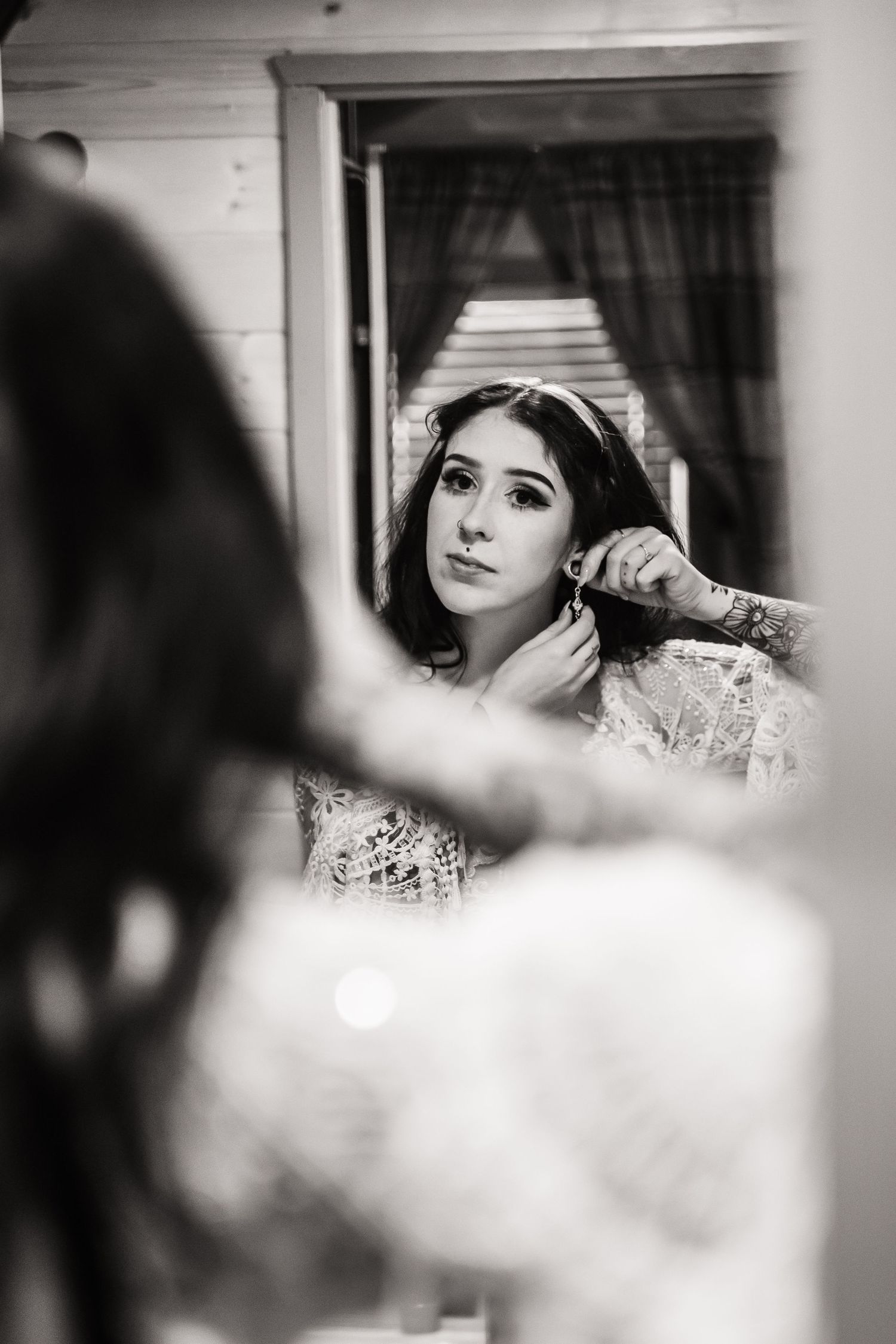 Black and white reflection of bride getting ready in mirror.