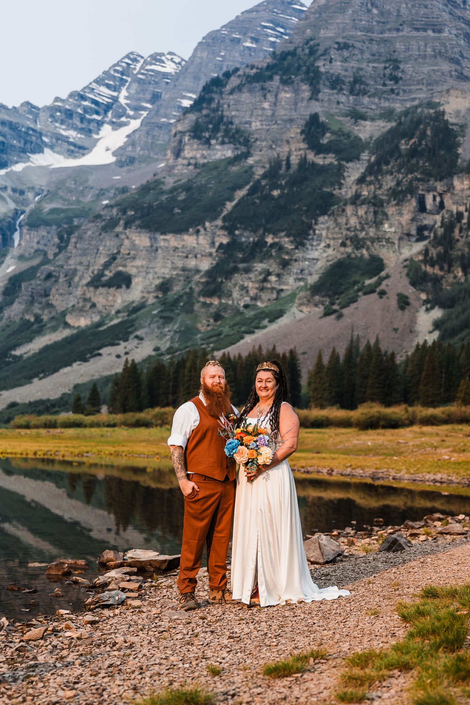 Bride and groom pose before stunning Maroon Bells mountain reflection lake during outdoor Colorado wilderness elopement.