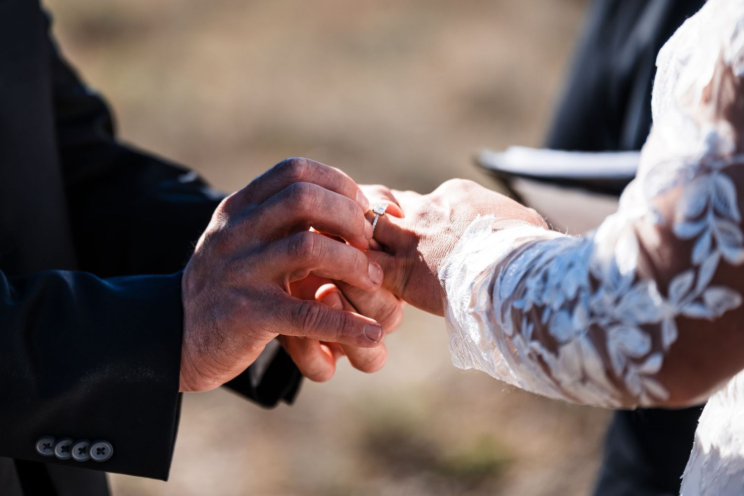 Close-up shot of hands exchanging wedding rings during a marriage ceremony.