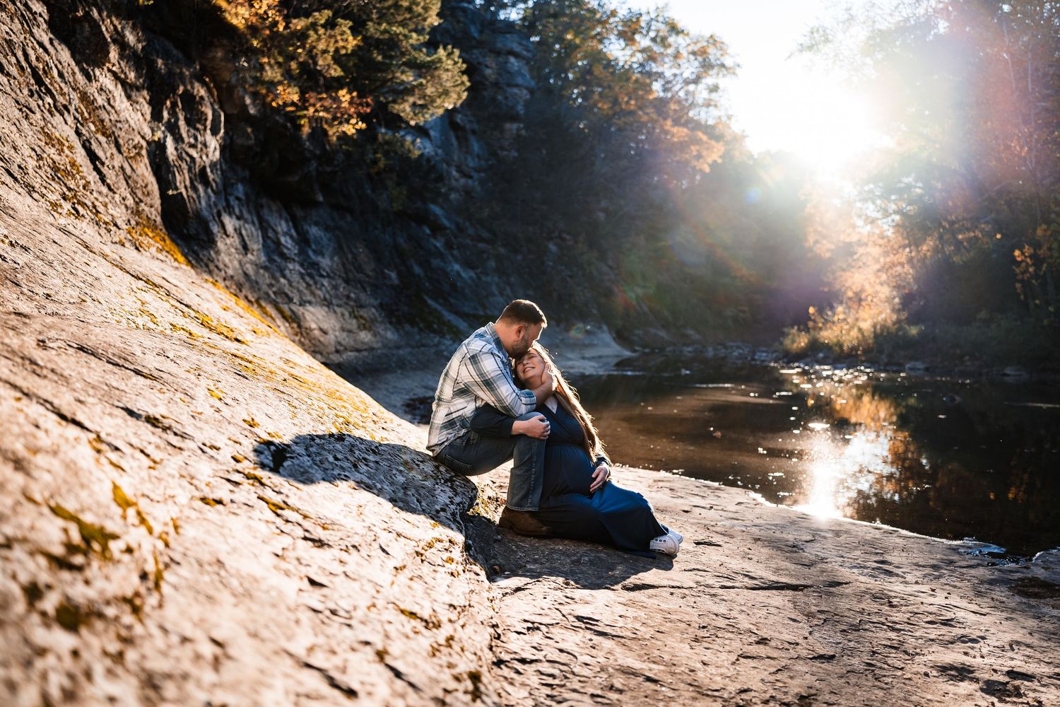 A person in a blue shirt rock climbing on a sunlit cliff face during golden hour.