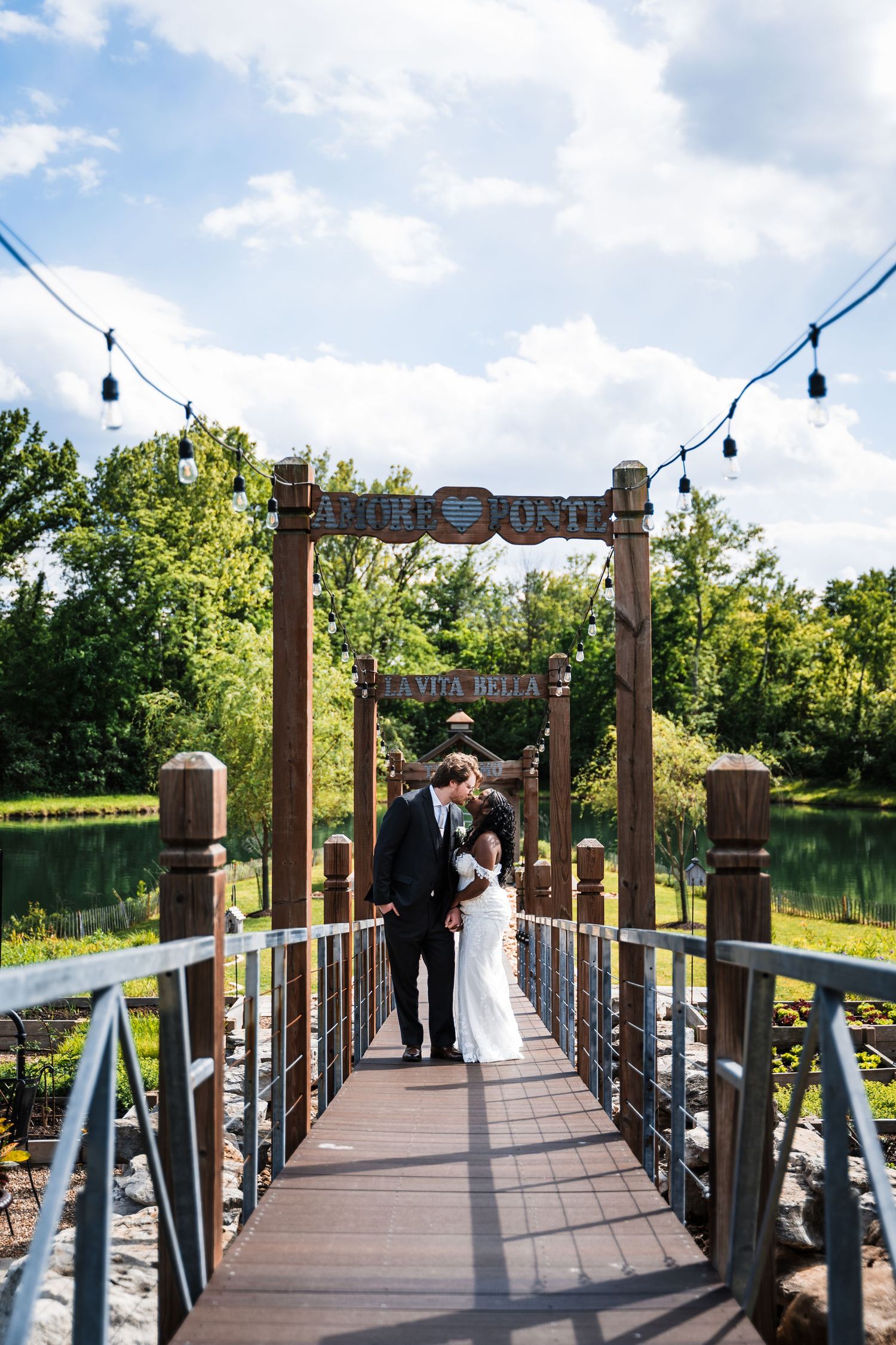 Bride and groom walking hand in hand on a wooden suspension bridge at Viva Bella wedding venue.