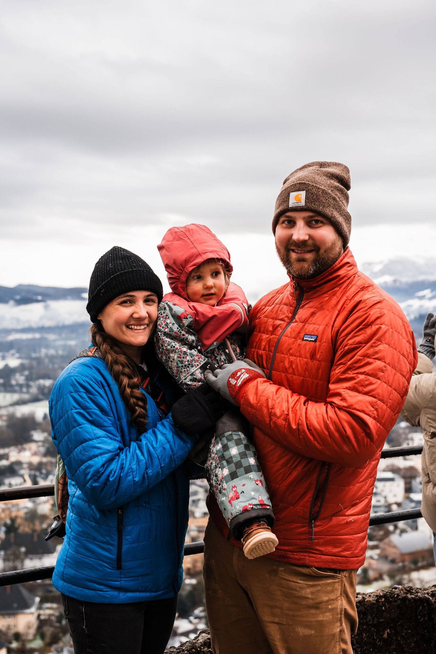 People in winter clothing share a joyful moment against a snowy mountain backdrop.
