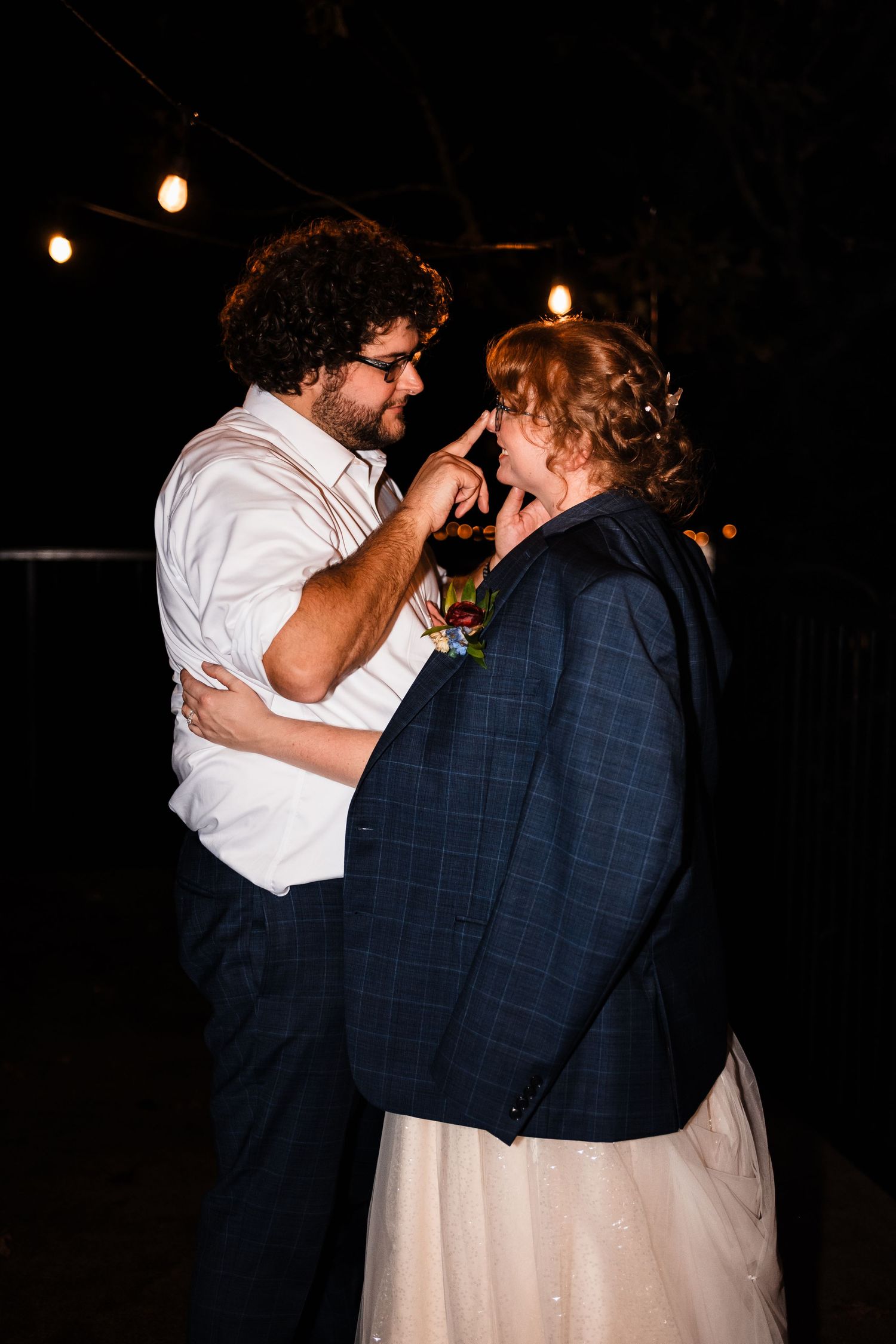 A couple shares an intimate dance moment under dim lighting at an evening event.