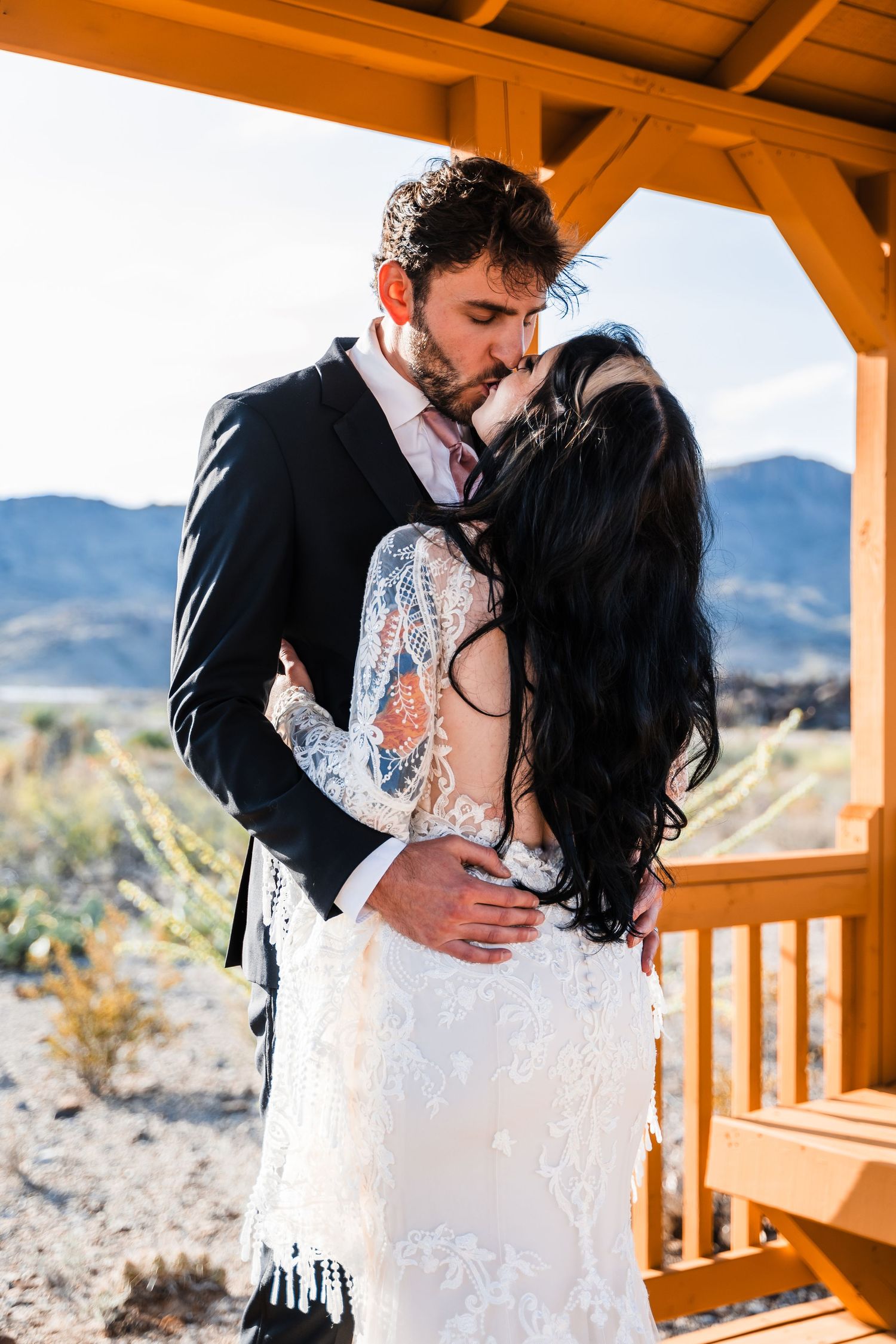 Romantic wedding portrait on wooden deck with desert mountain backdrop.