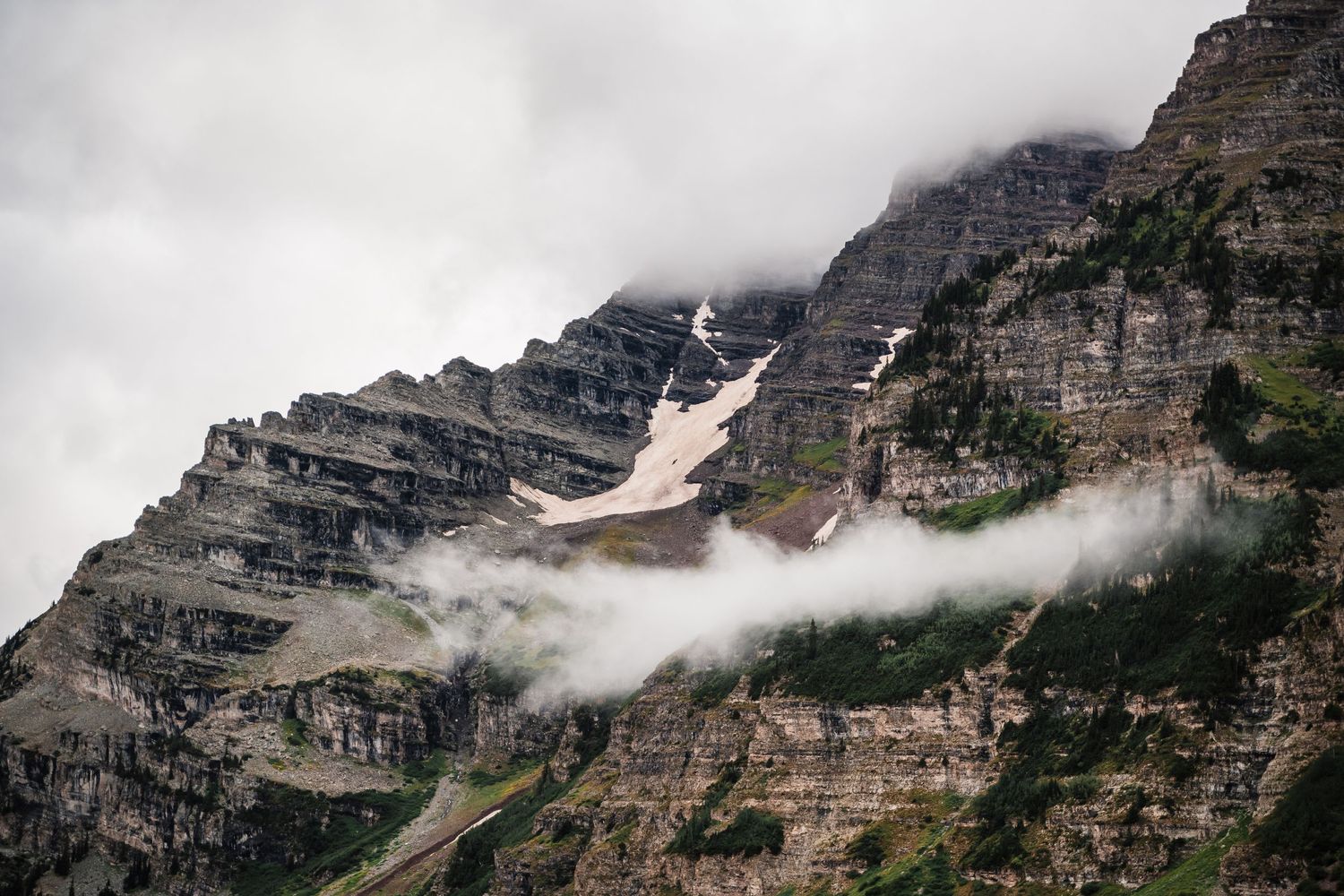 Majestic layered mountain peaks partially shrouded in misty clouds with snow patches.