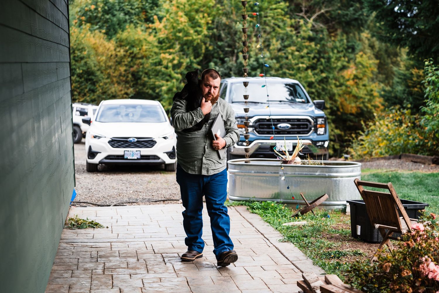 Person standing on a stone path between parked Mercedes vehicles in a garden driveway setting.