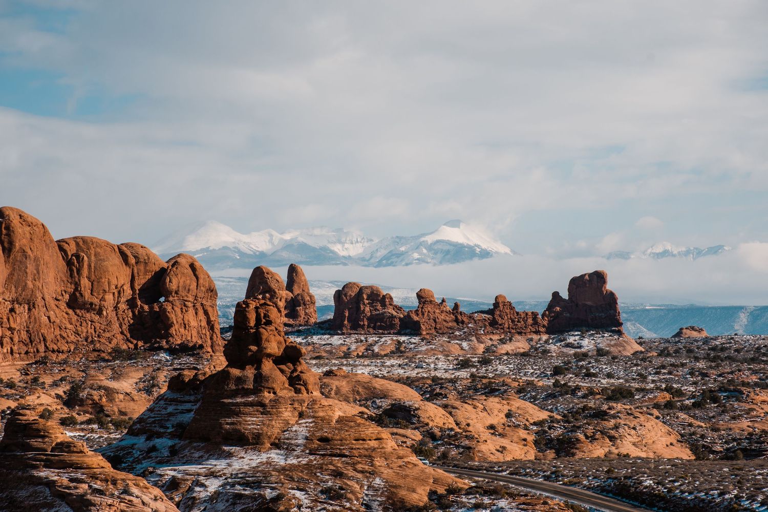 Dramatic red rock formations and desert landscape under cloudy skies at Arches National Park in Utah.