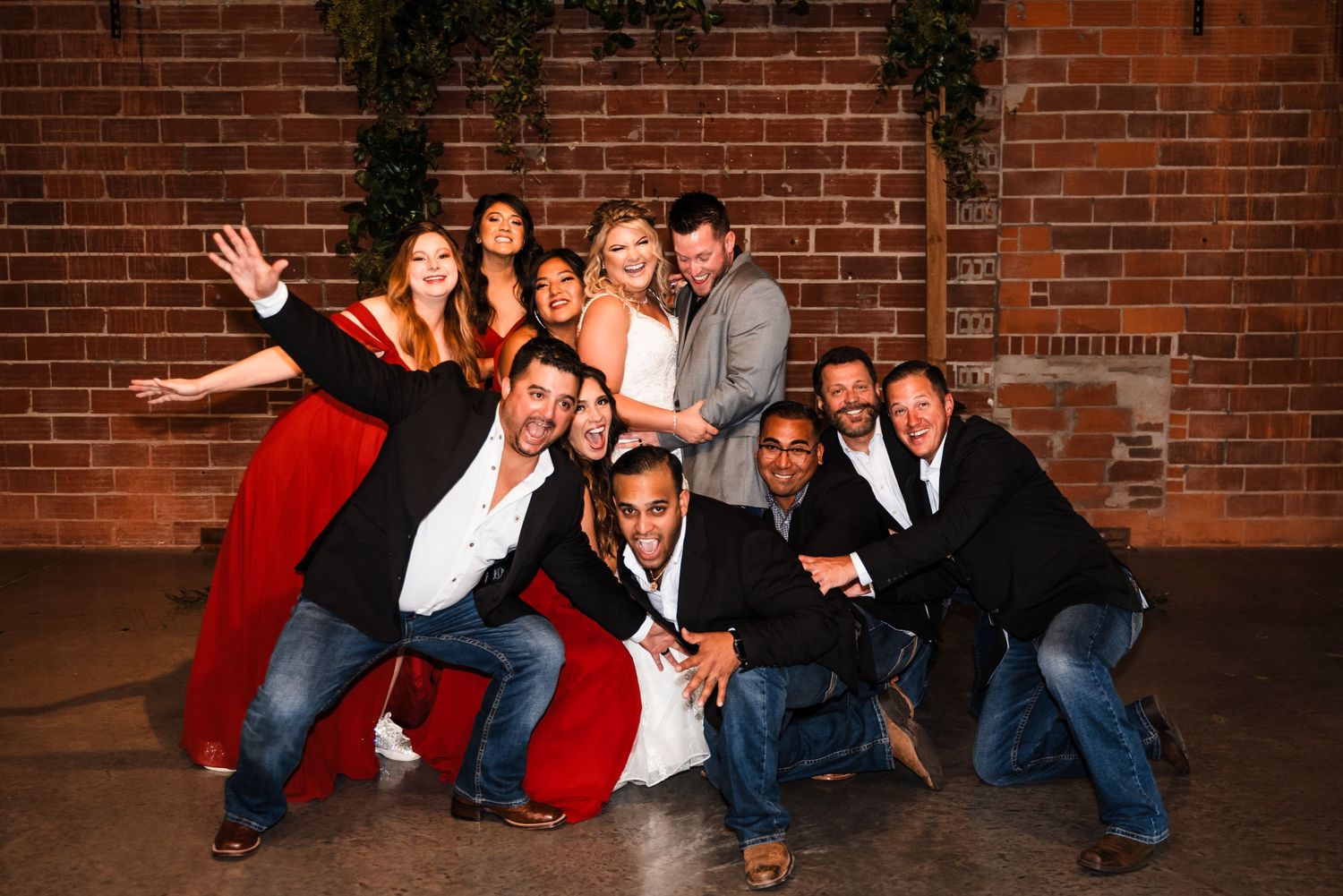 A fun group photo of party guests posing casually against a brick wall background.
