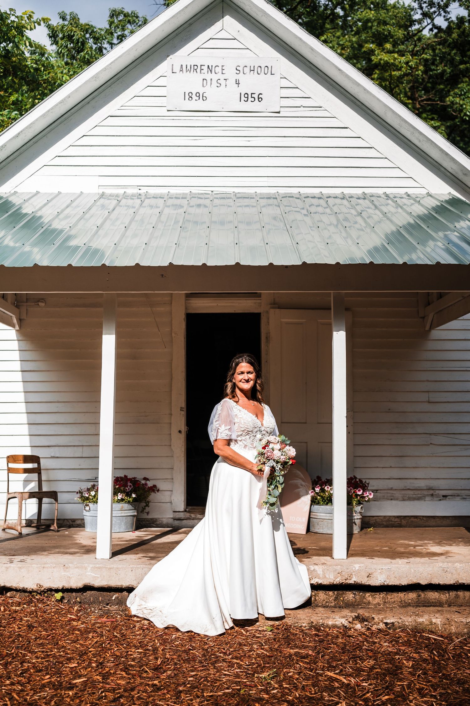 Wedding portraits taken in front of a historic white schoolhouse with 1856 marking.