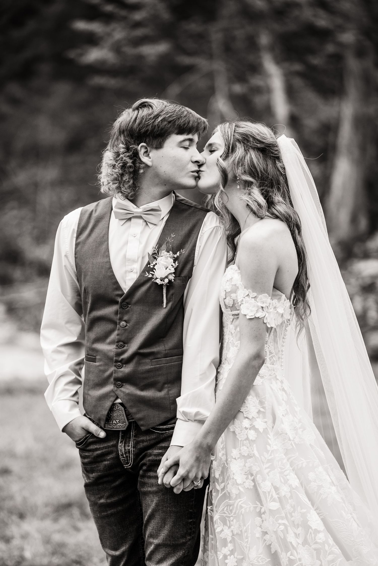 Intimate black and white portrait of newlyweds sharing a tender moment outdoors.