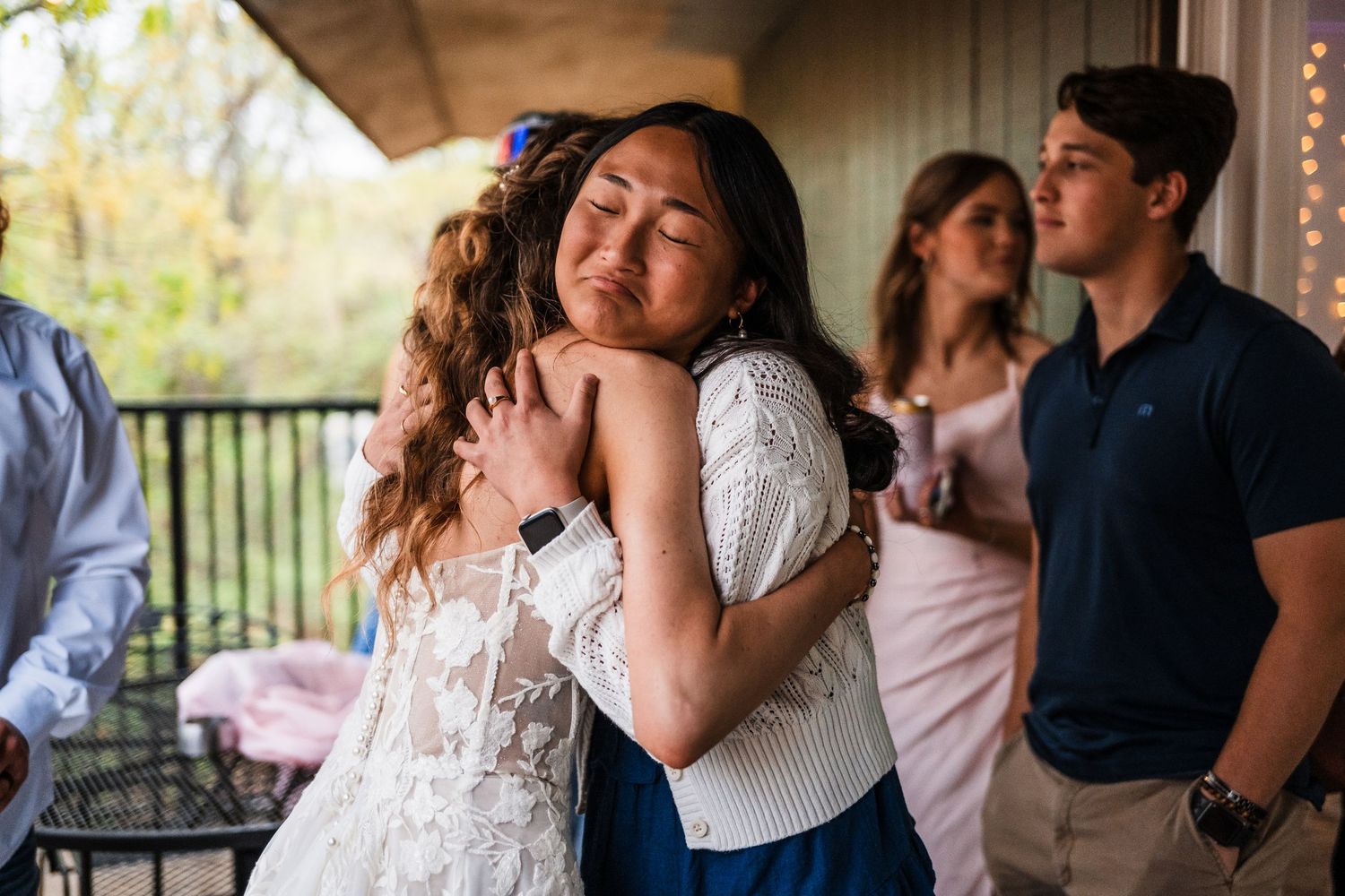Emotional embrace between two people at a wedding celebration on an outdoor patio.