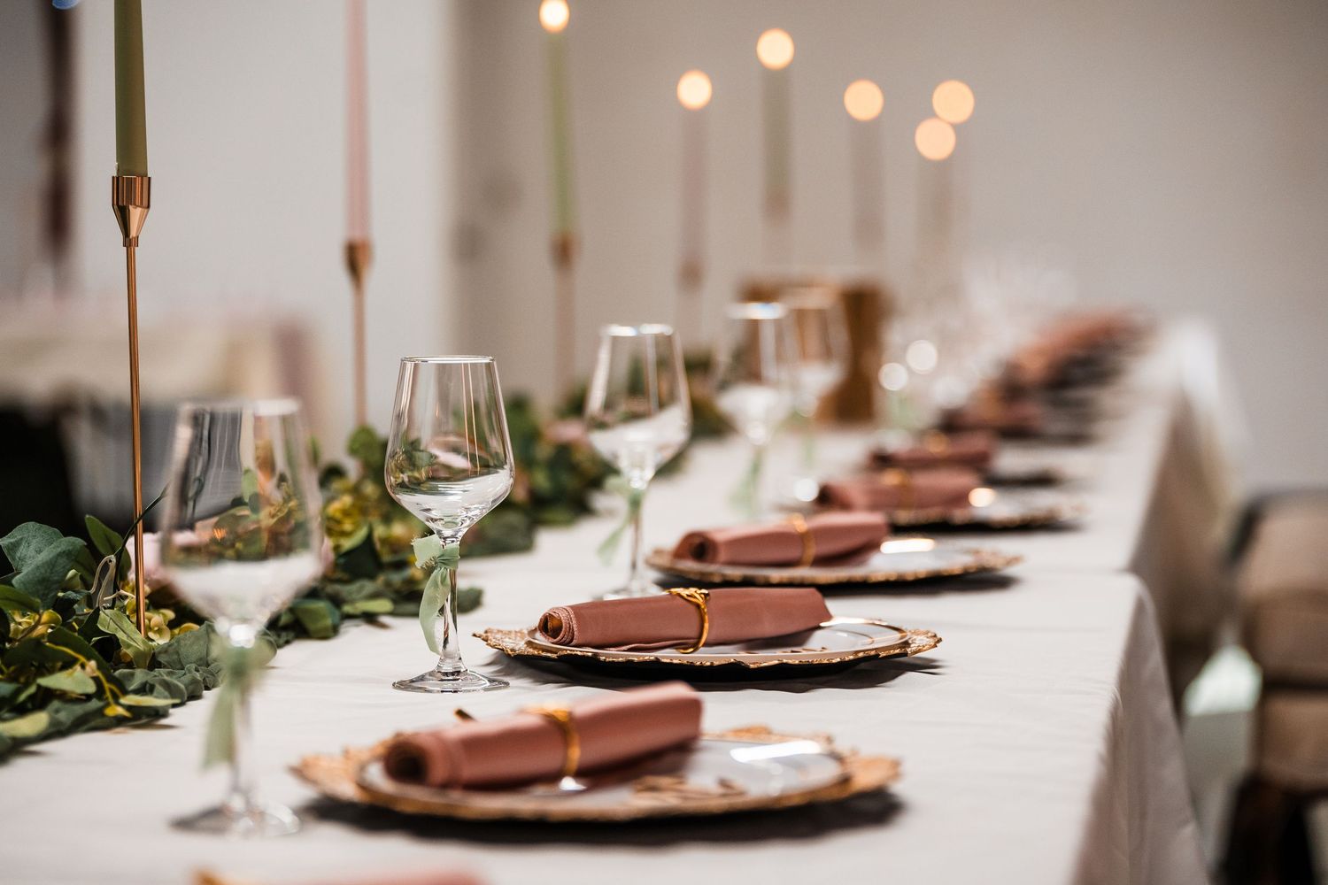 Elegant table setting with copper chargers, white plates and soft lighting at a formal dining event.