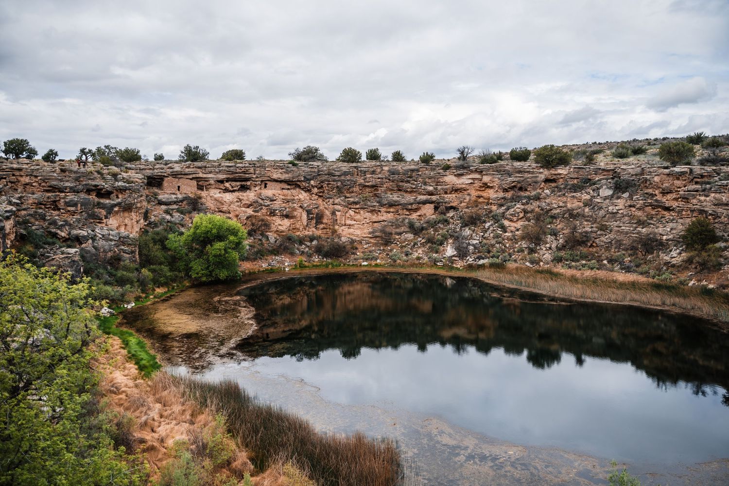 Montezuma Well, a natural limestone sinkhole with still waters surrounded by desert landscape.