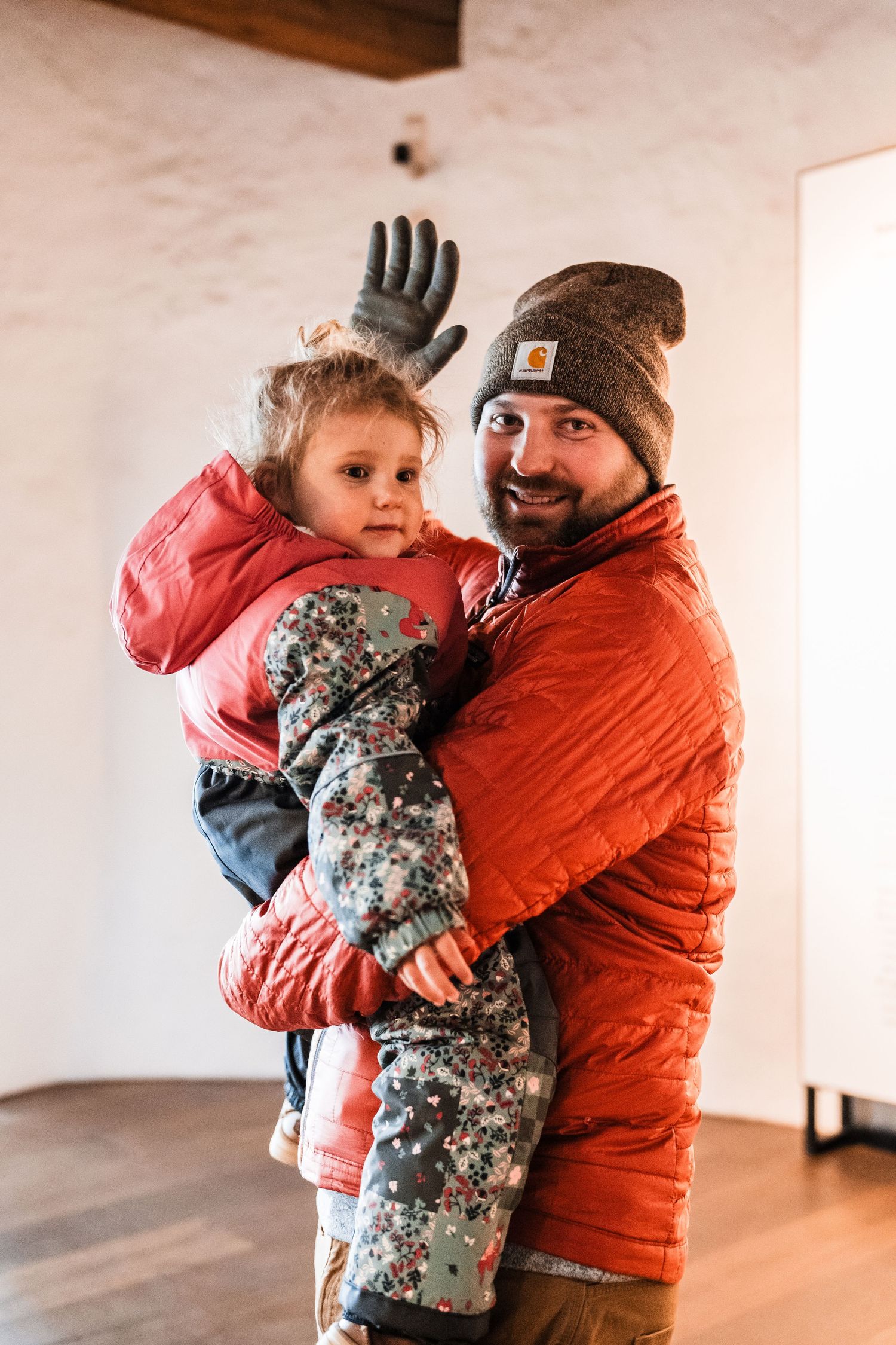 A heartwarming embrace between two people wearing winter coats indoors.