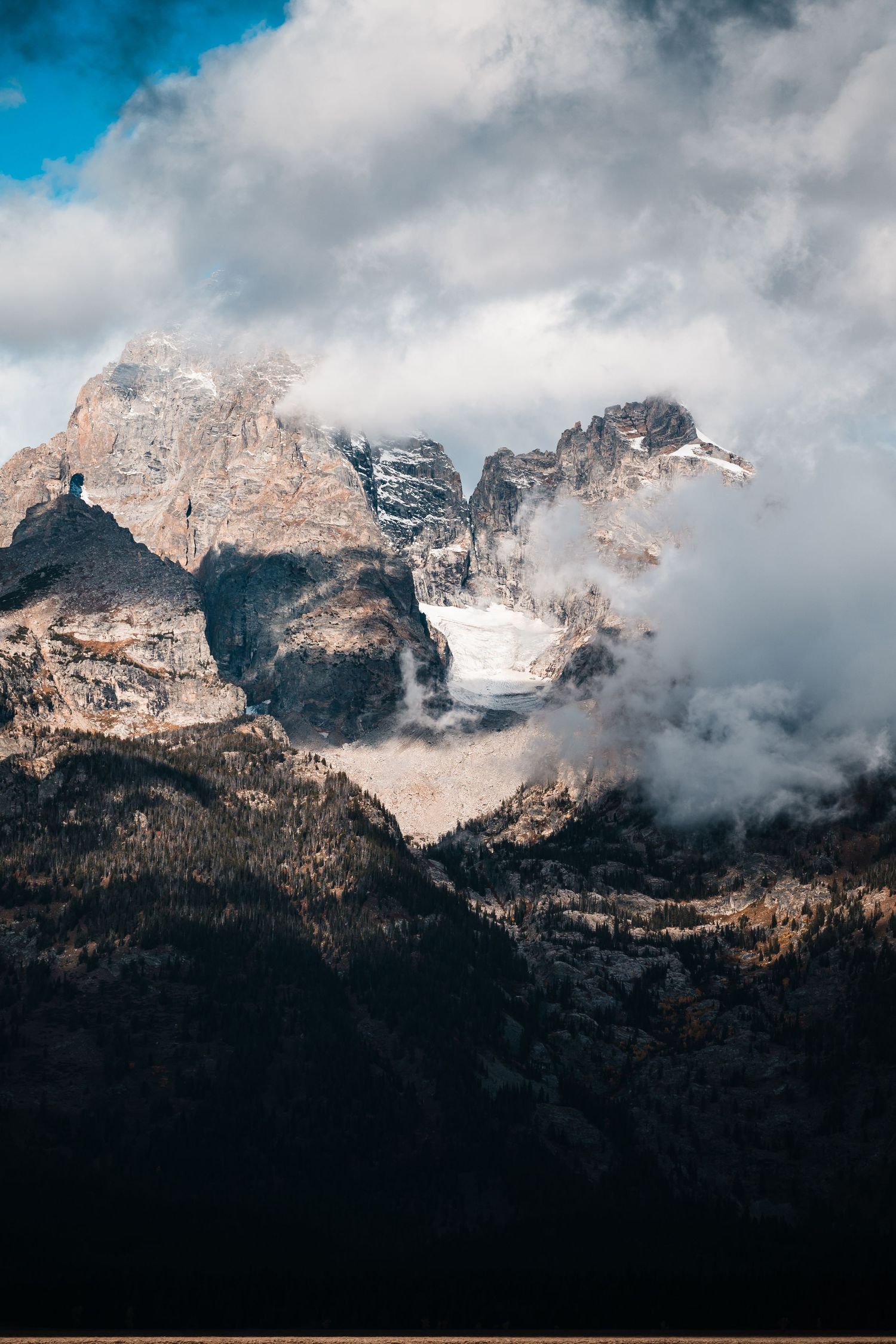 Dramatic mountain peaks with snow patches and swirling clouds against a moody sky in the Dolomites range.