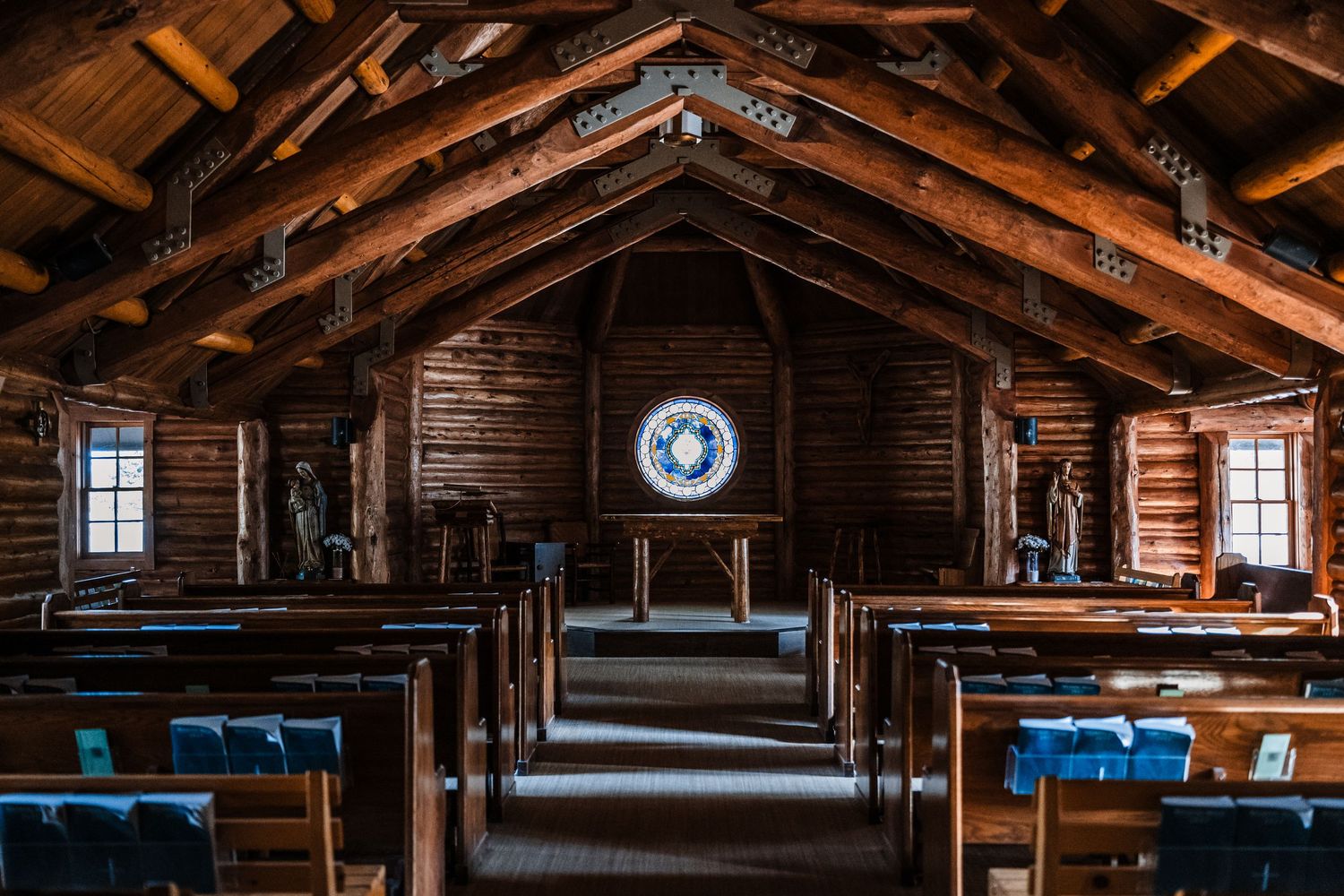 Interior of rustic wooden cabin with exposed beams and windows letting in natural light.