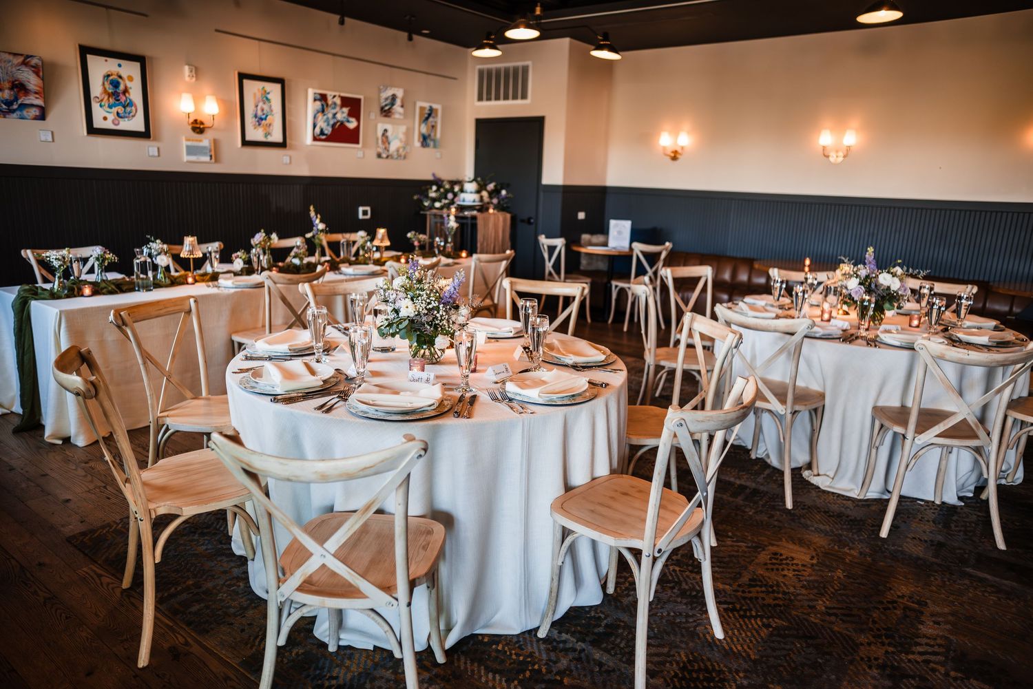 Elegant wedding reception venue with round tables, white linens, and cross-back chairs.
