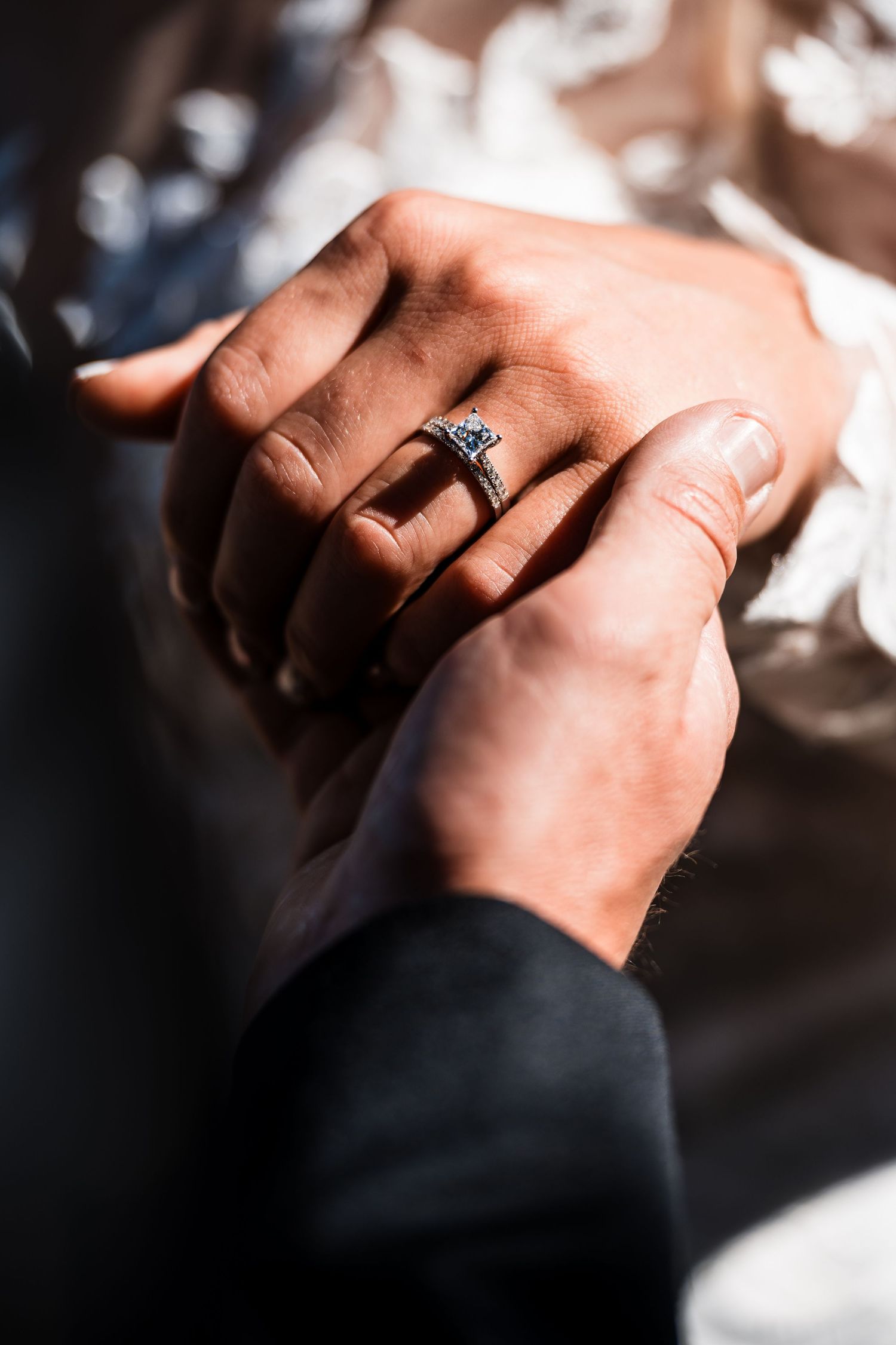 Close-up shot of hands displaying an elegant diamond engagement ring.