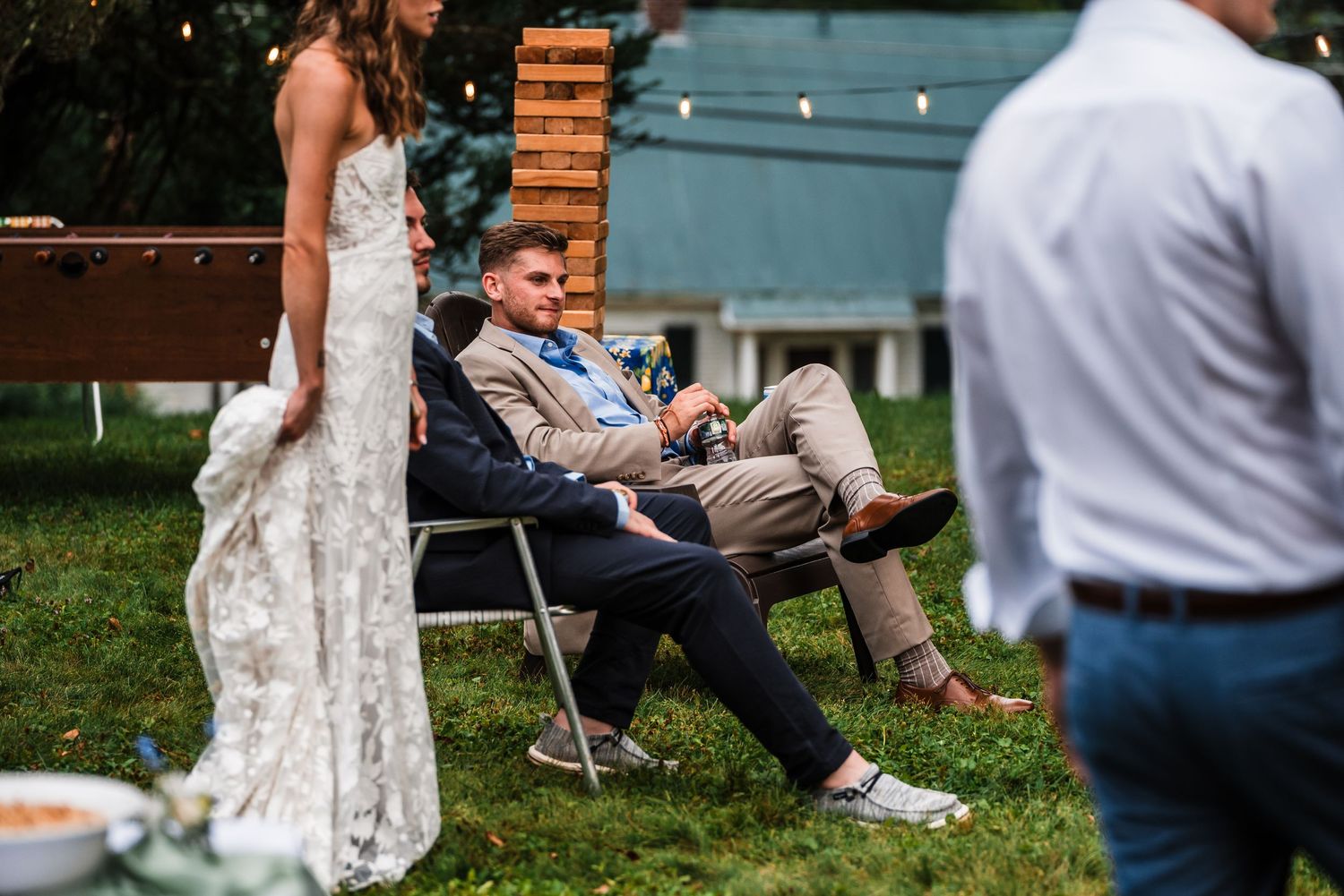 Casual outdoor wedding reception with guests relaxing in lawn chairs.