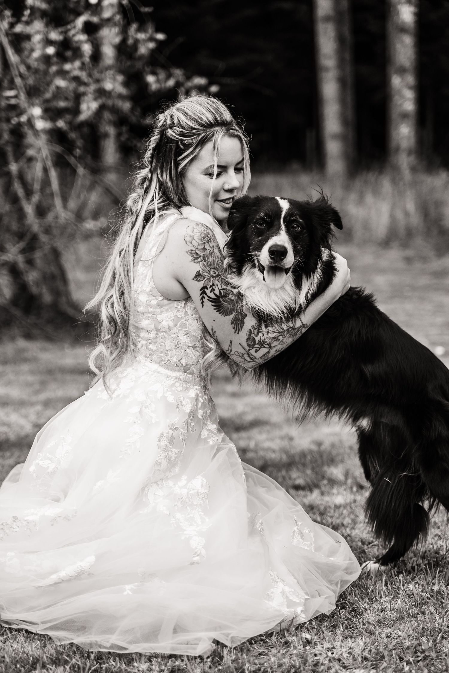 A black and white portrait with a Border Collie and white wedding dress in a forest setting.
