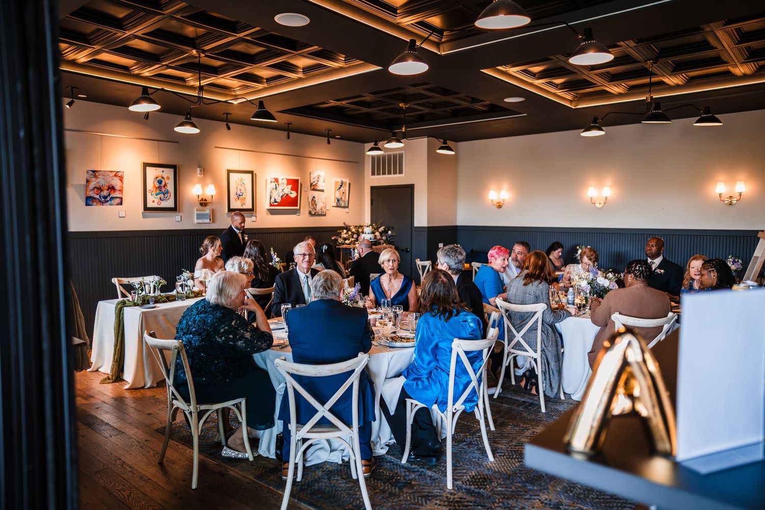 Guests seated at round tables during intimate wedding reception in stylish restaurant venue.