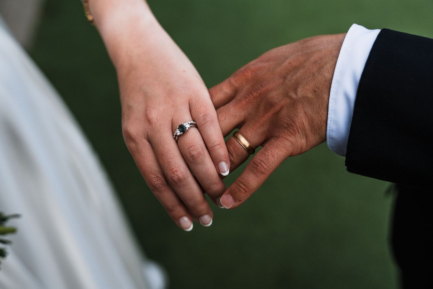 Close-up of bride and groom hands showing wedding rings after outdoor ceremony.